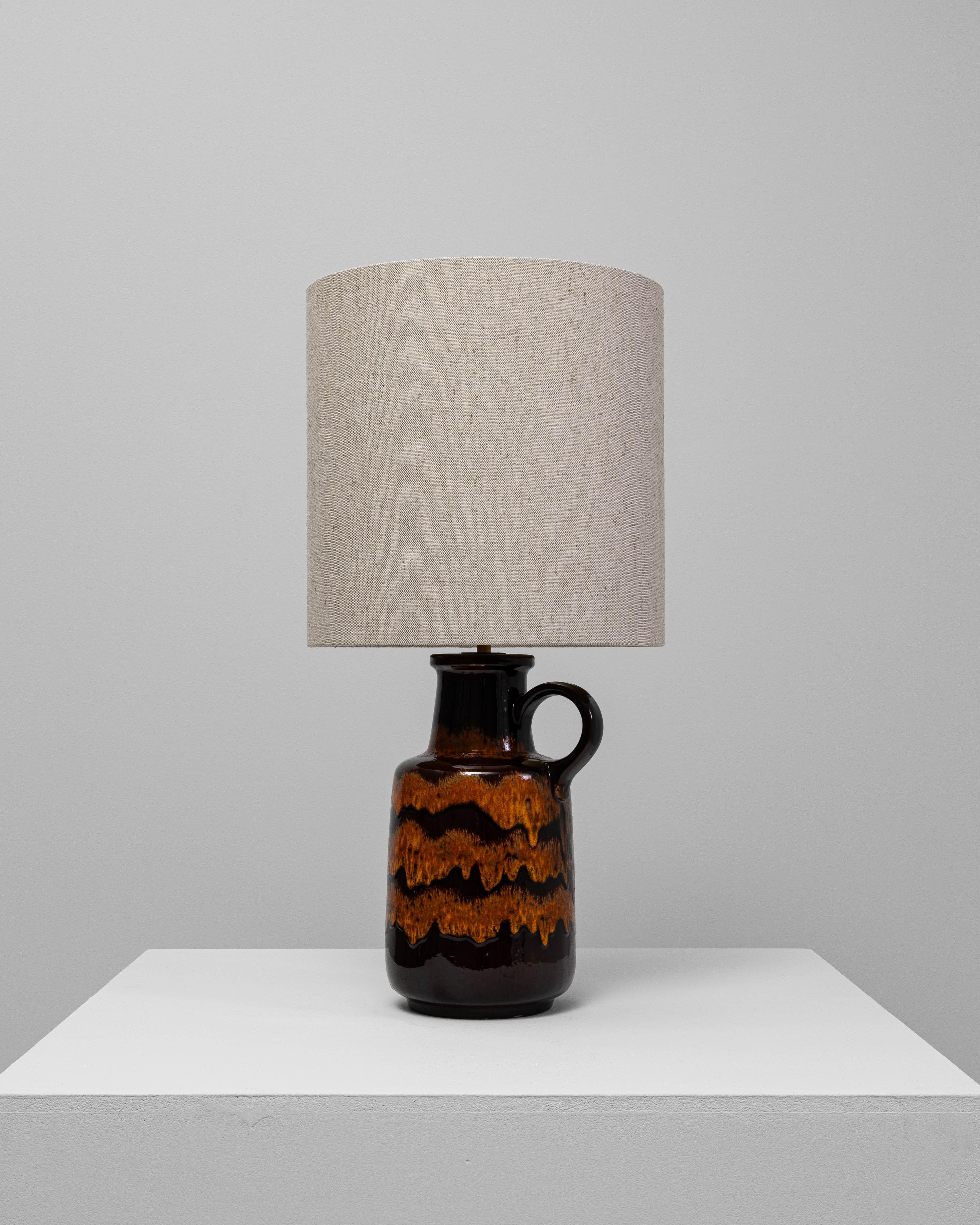 Cette lampe de table en céramique orange à glaçure goutte à goutte du 20e siècle est un exemple frappant de la poterie européenne du milieu du siècle, définie par sa riche coloration et sa surface tactile. La forme inspirée de la cruche présente un