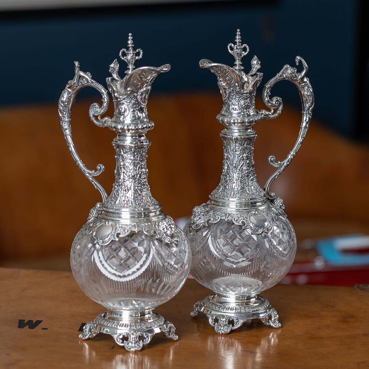 Paire de cruches à vin allemandes en argent massif, de taille exceptionnelle, datant du début du 20e siècle. Chaque corps en verre taillé est élégamment gravé de motifs en forme de guirlandes et de hachures, tandis que les montures en argent