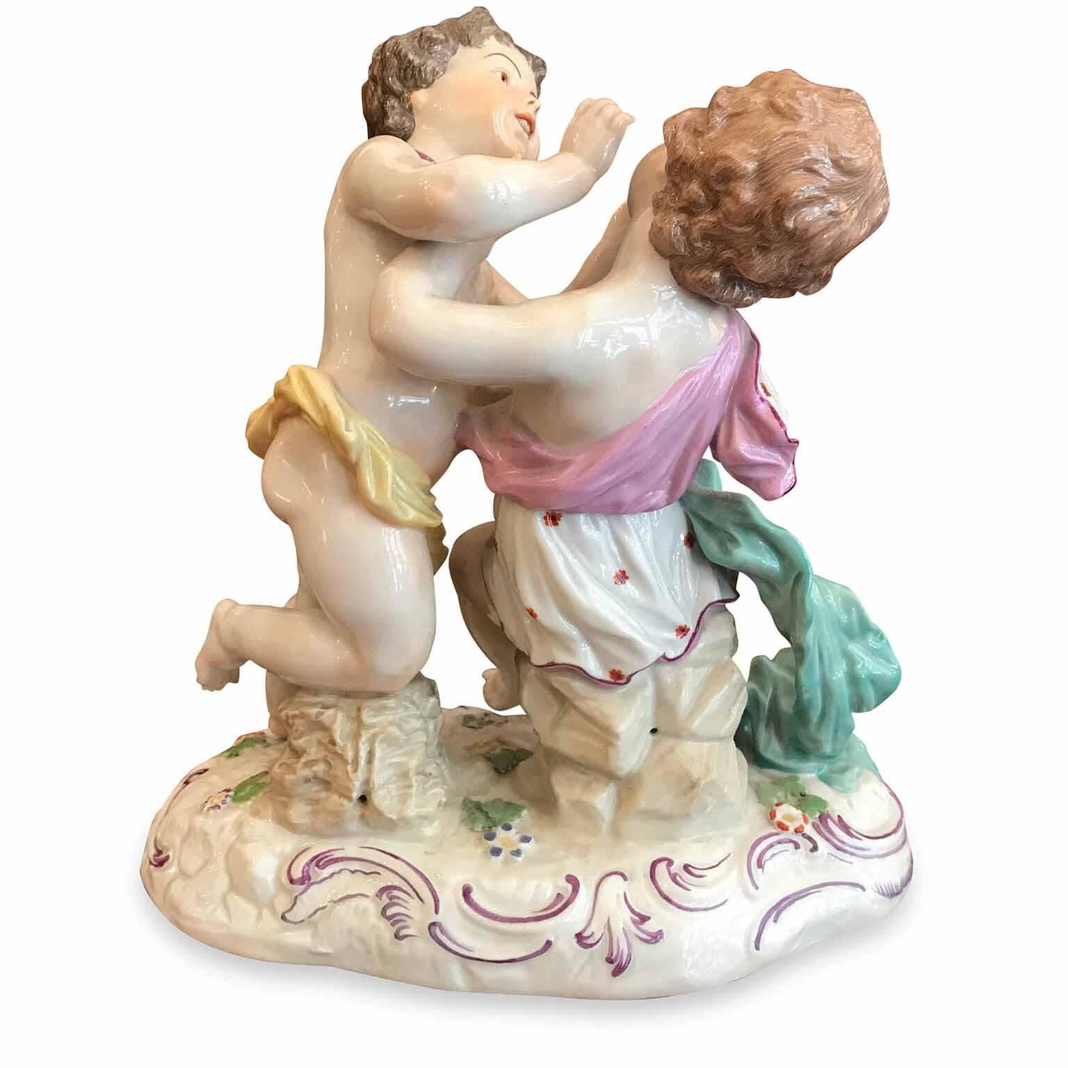 A 20th century bright and polychrome Passau German Porcelain group with Cherubs, a very decorative antique German porcelain sculpture featuring two playing cherubs on an oval base. . 
This antique German hand painted figural porcelain shows the