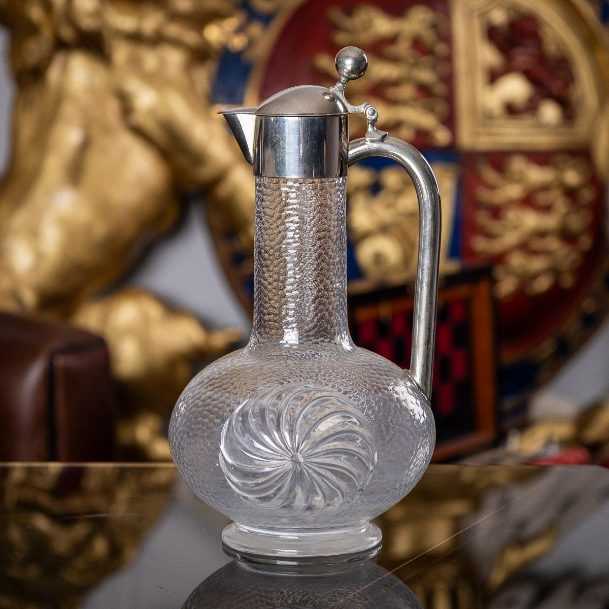 20th century German solid silver & etched glass claret jug, the baluster body beautifully hand engraved imitating a hand-hammered effect, and sides decorated with a round spiral, the plain solid silver collar mounted with a hinged lid, ball shaped