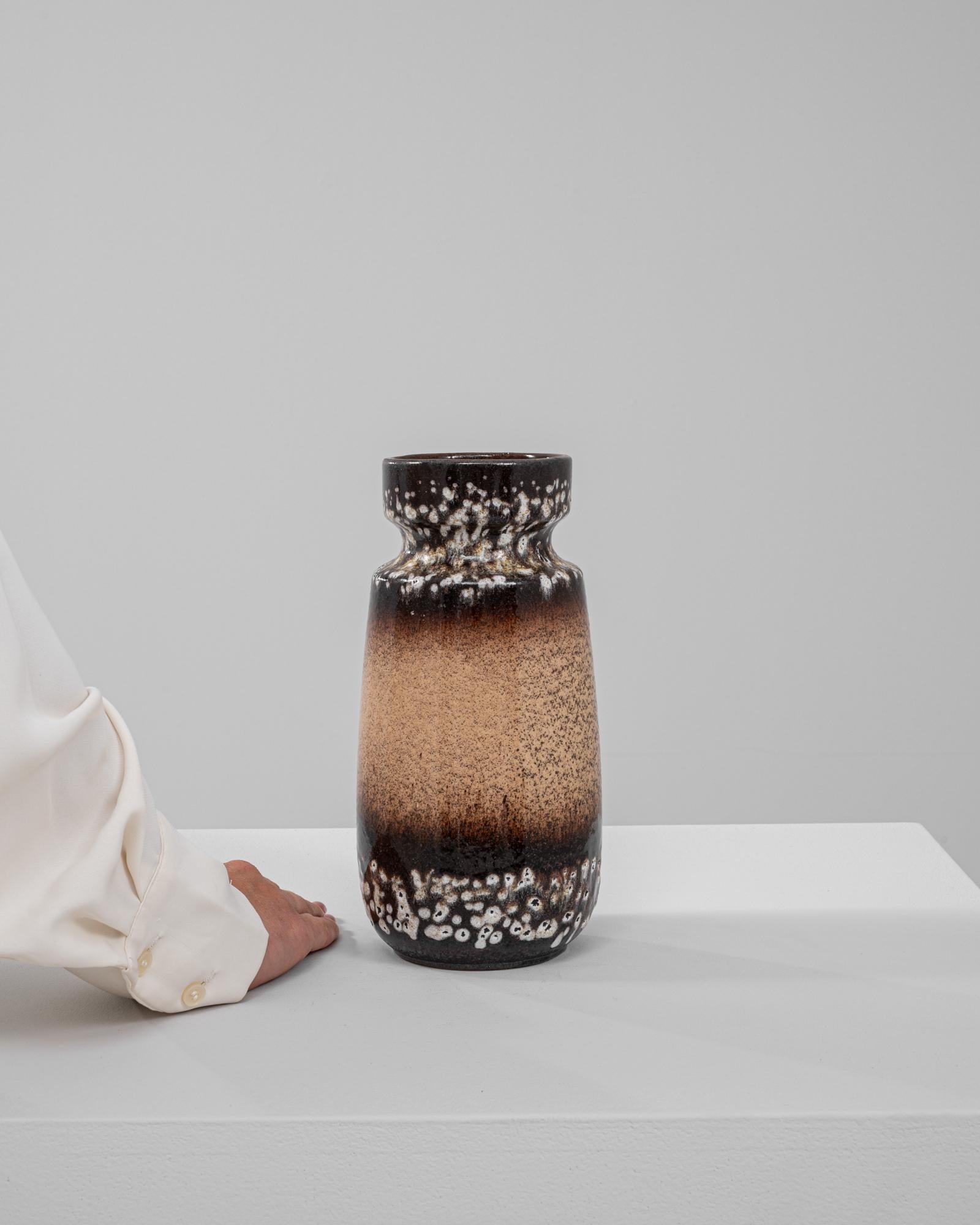 Questo straordinario vaso in ceramica della Germania Occidentale del XX secolo esemplifica l'audace e innovativa tecnica di smaltatura lavica tipica dell'epoca. Il vaso presenta una superficie strutturata con un gradiente dinamico, che passa dal