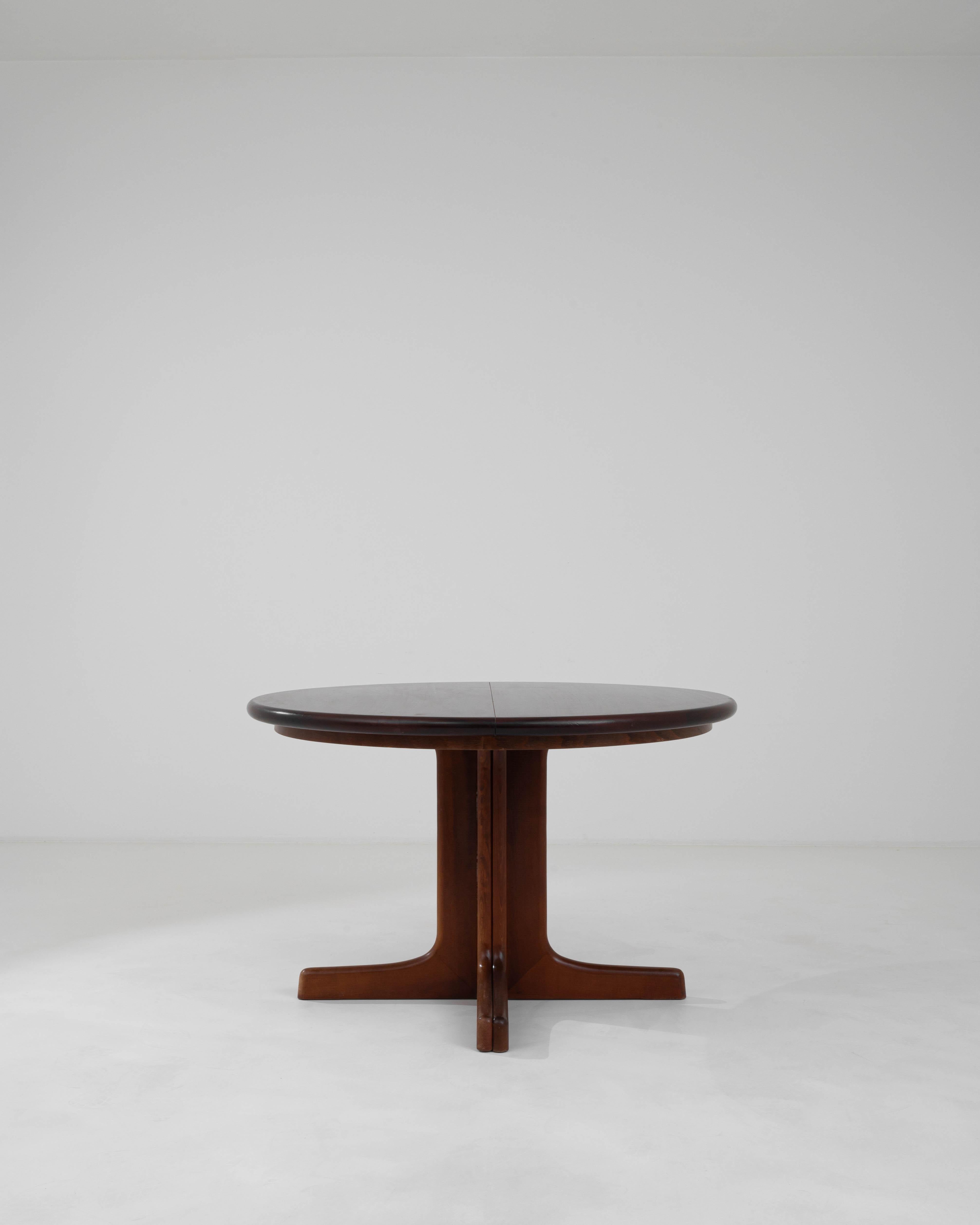 This 20th Century German Wooden Dining Table by Casala presents a harmonious blend of robust functionality and sleek design. The table's circular form encourages intimate gatherings, with its rich wooden top offering a warm and inviting surface for