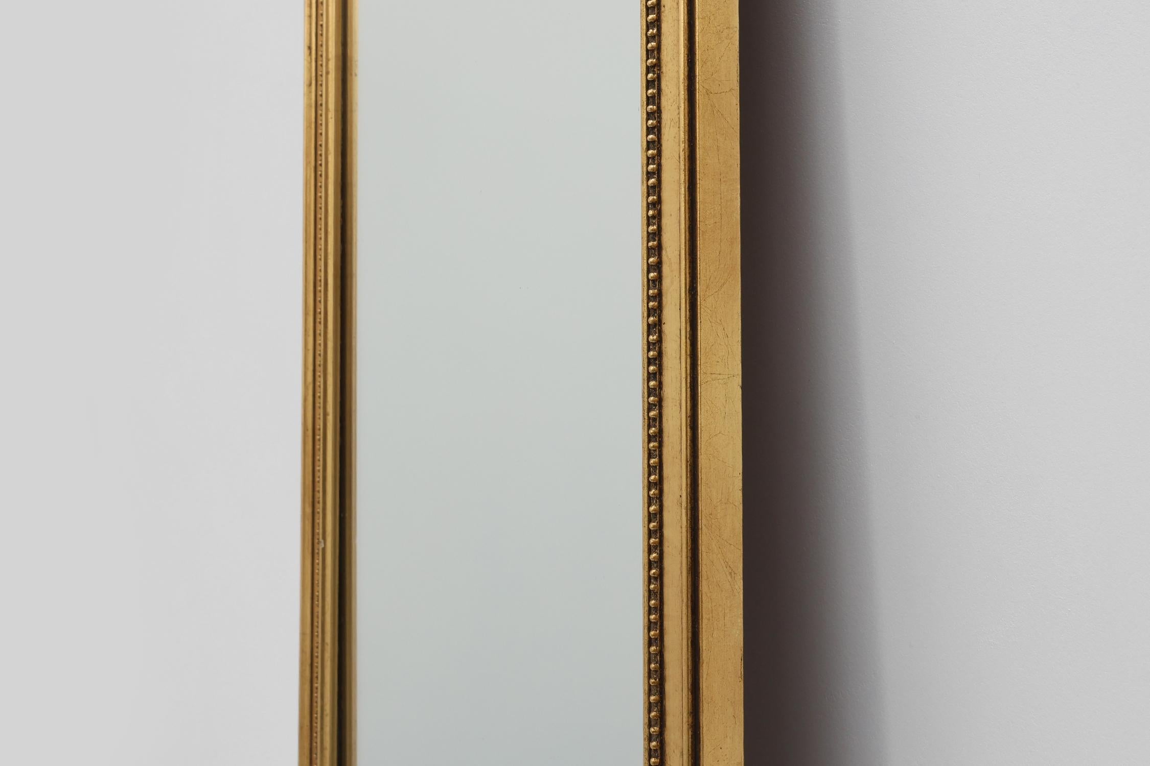 Metà XX secolo 20th Century gilded wooden Empire style mirror with eagle on top in vendita