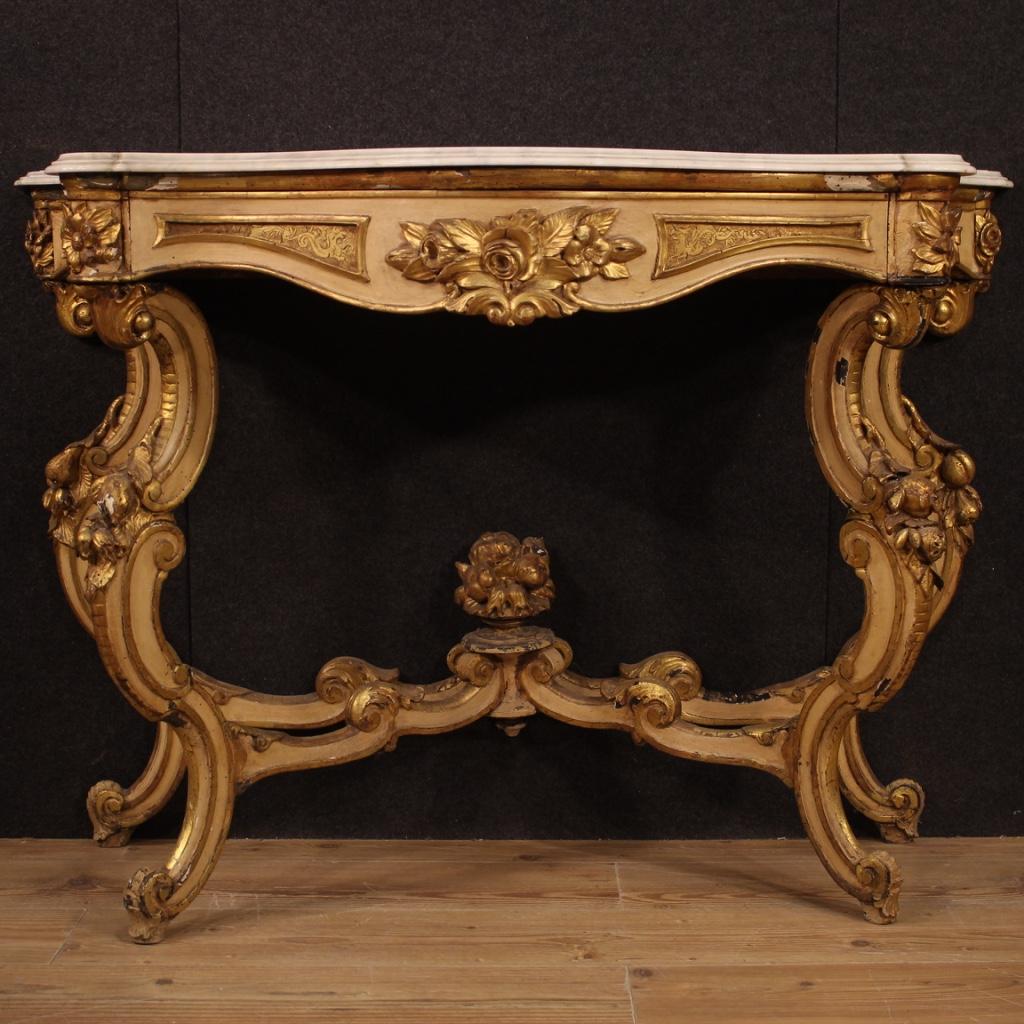Italian console from the mid-20th century. Furniture in carved, lacquered and gilded wood in Louis Philippe style. Wall console supported by four wavy legs with central connection, richly adorned with decorations with flowers and fruit (see photo).