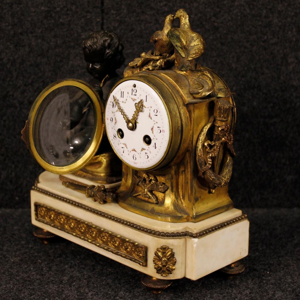 Italian clock from the early 20th century. Object in gilded and chiseled bronze, brass and metal with marble base. Object for antique dealers and collectors equipped with original painted metal clock face. Missing key, it has small signs of wear.