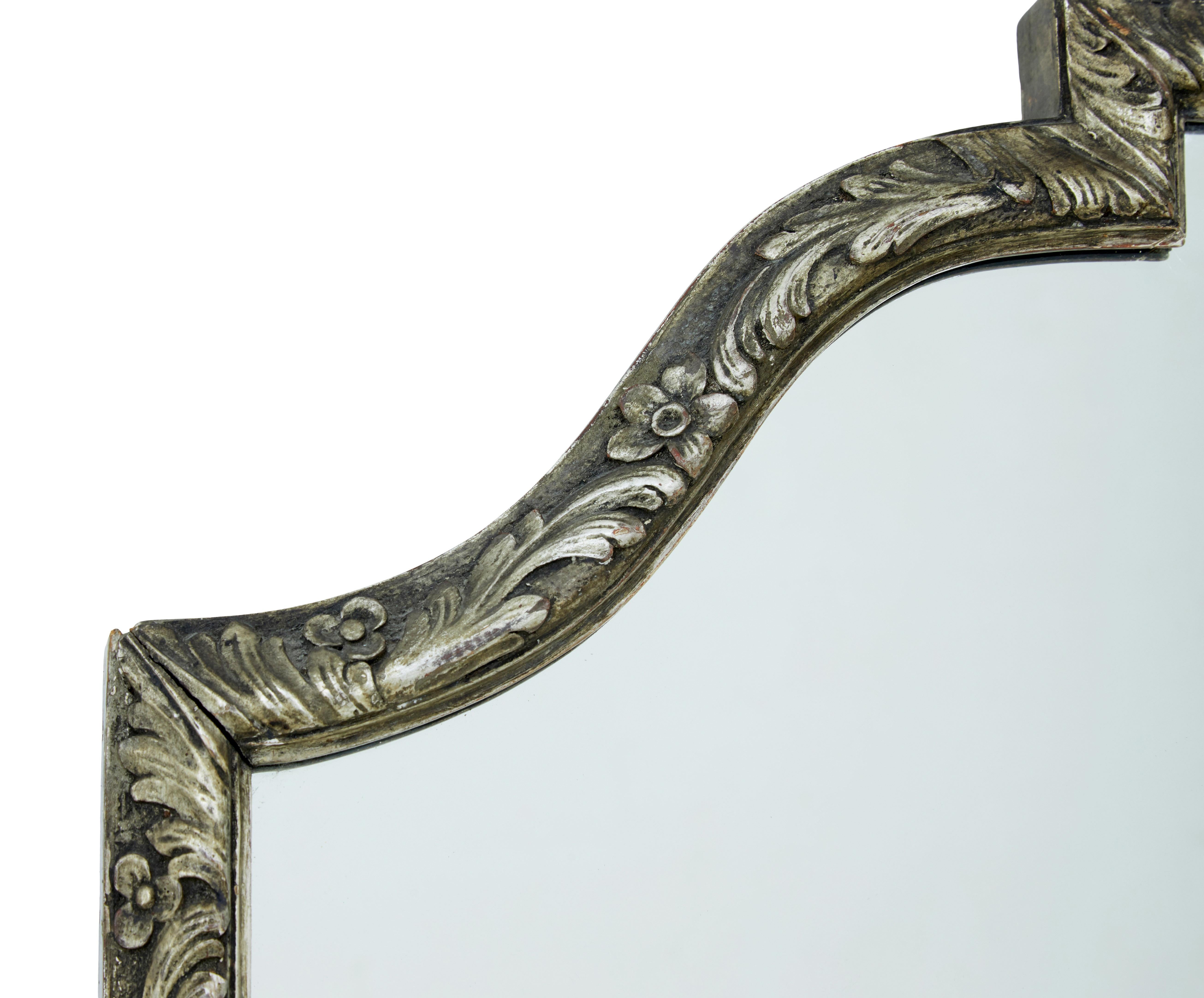 Good sized shaped wall mirror, circa 1920.

Rectangular main shape, detailed with carved swags and florals. Mounted with a large carved shell.

Minor losses to gilt and gesso.