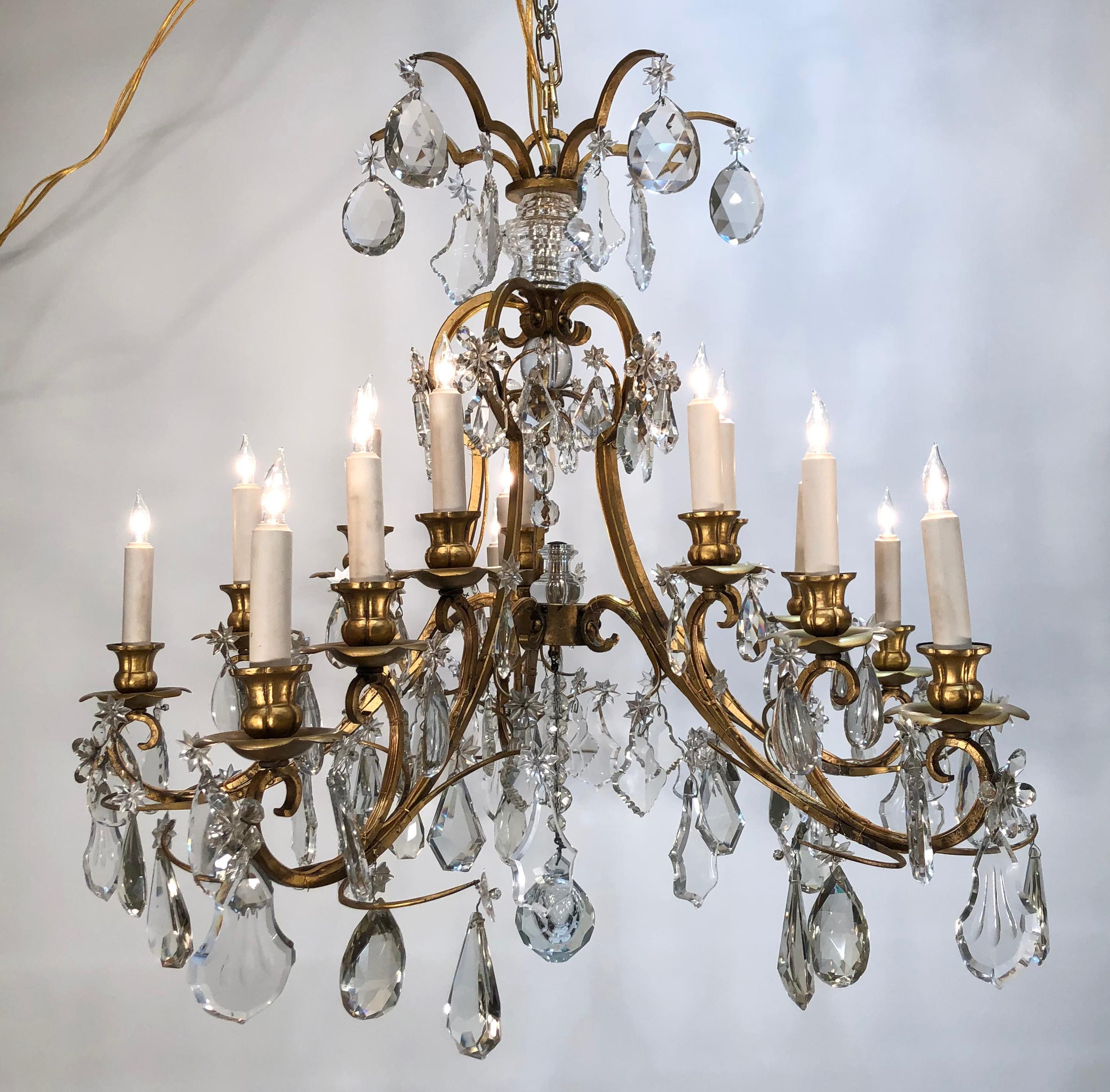  This magnificent Early 20th Century Grand Gilt Iron and Crystal Chandelier is of the Chinoiserie Style. This chandelier exhibits high quality wrought iron, pinned and screwed with the highest quality of crystal. The bobeches and candle cups are