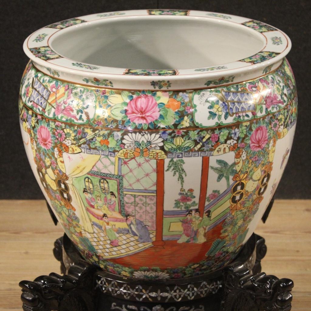 Grand vase chinois du 20ème siècle. Fabuleux objet en céramique émaillée, dorée et peinte à la main avec des décorations florales et animales. Vase orné de deux scènes intérieures avec des personnages de style oriental (voir photo). Base en bois