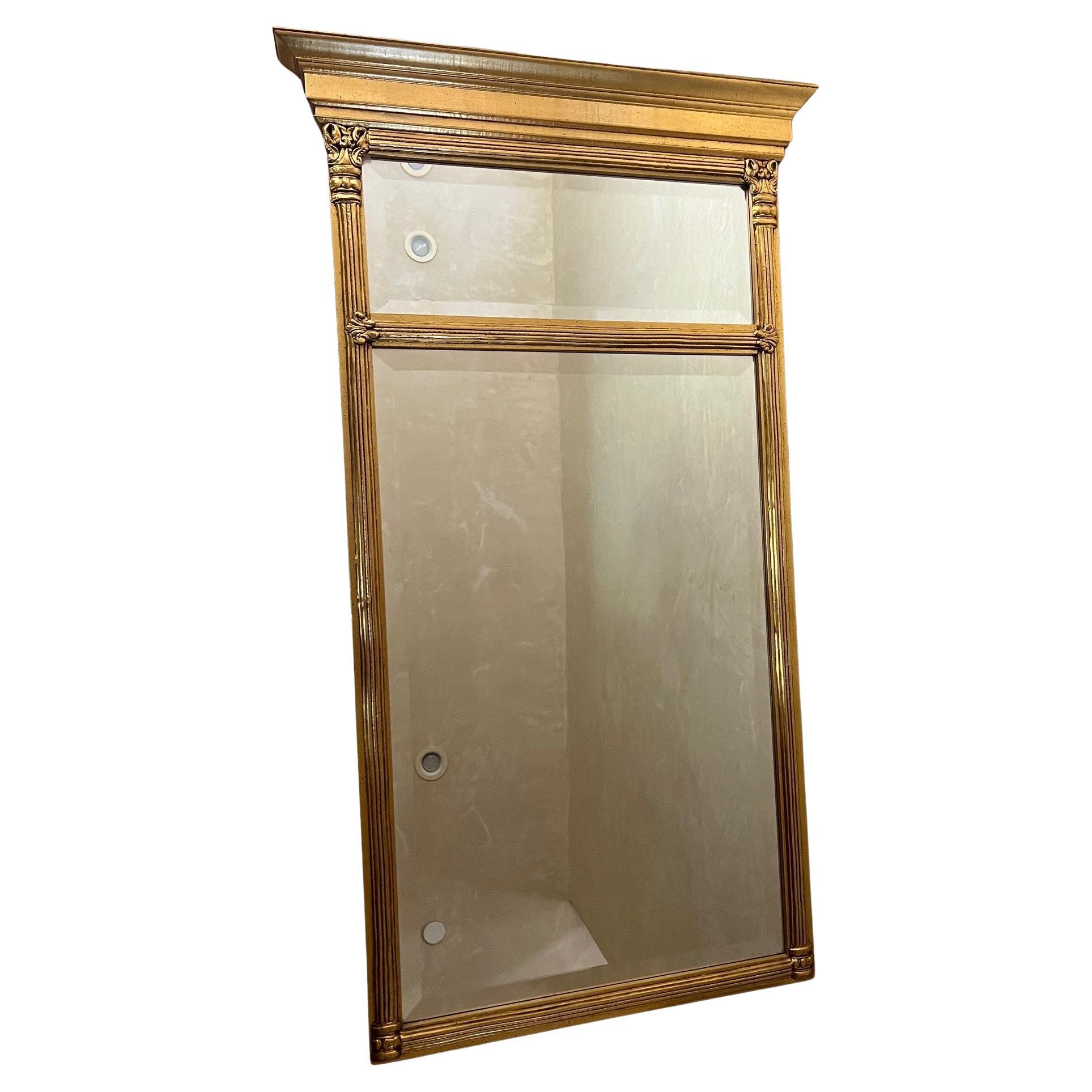 Vintage Empire style beveled pier mirror in giltwood frame.  Mirror has two sections a smaller rectangle on the top and longer on the bottom. The top sides form columns with fleur de lis style decor between the two mirrors.

Can be picked up for