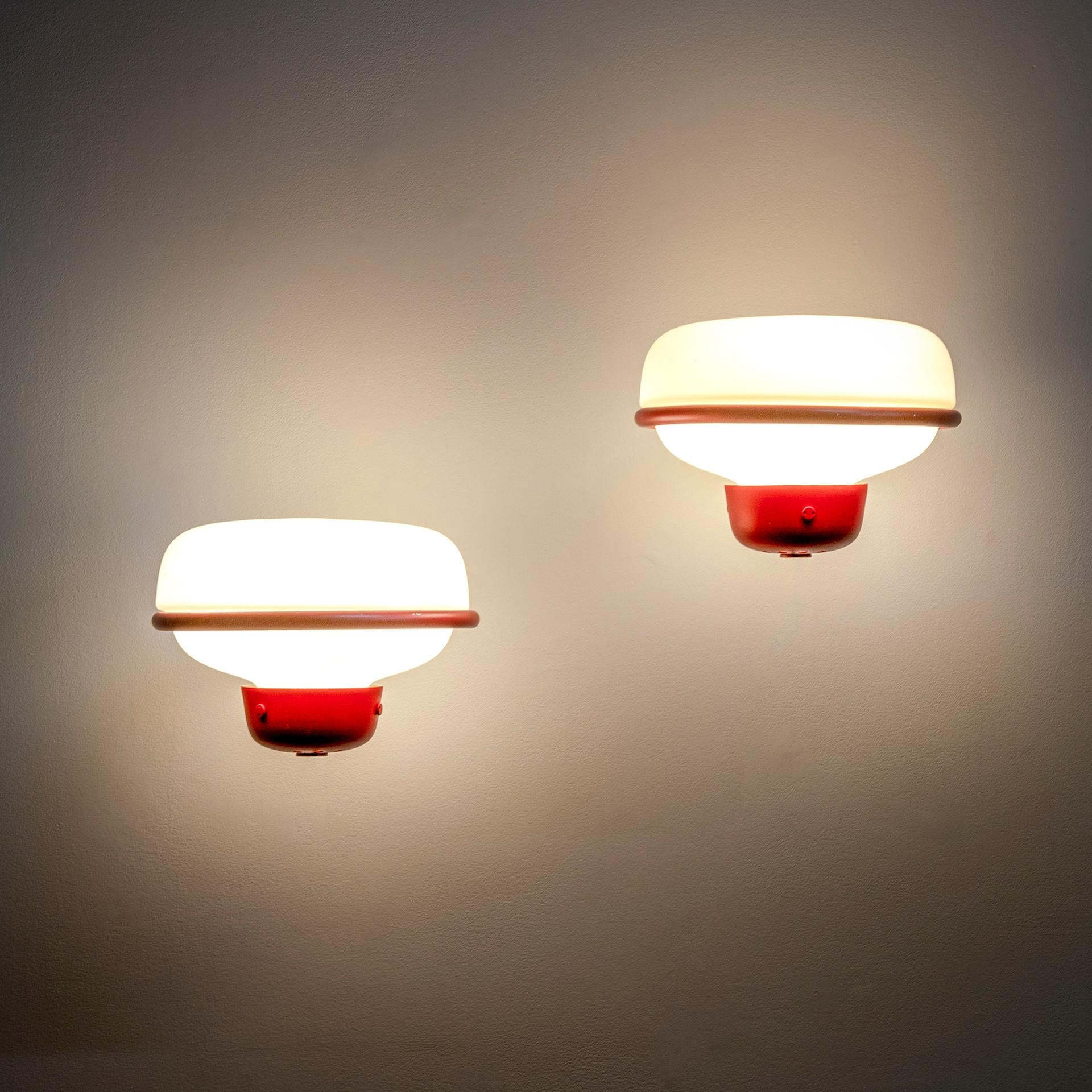 A couple of Wall lamps model 228 designed by the master of light Gino Sarfatti for Arteluce in 1957. The structure is in lacquered brass, the diffuser is in Opaline Glass. Red color. 
Presence of the brandmark Arteluce.
1 more couple eventually
