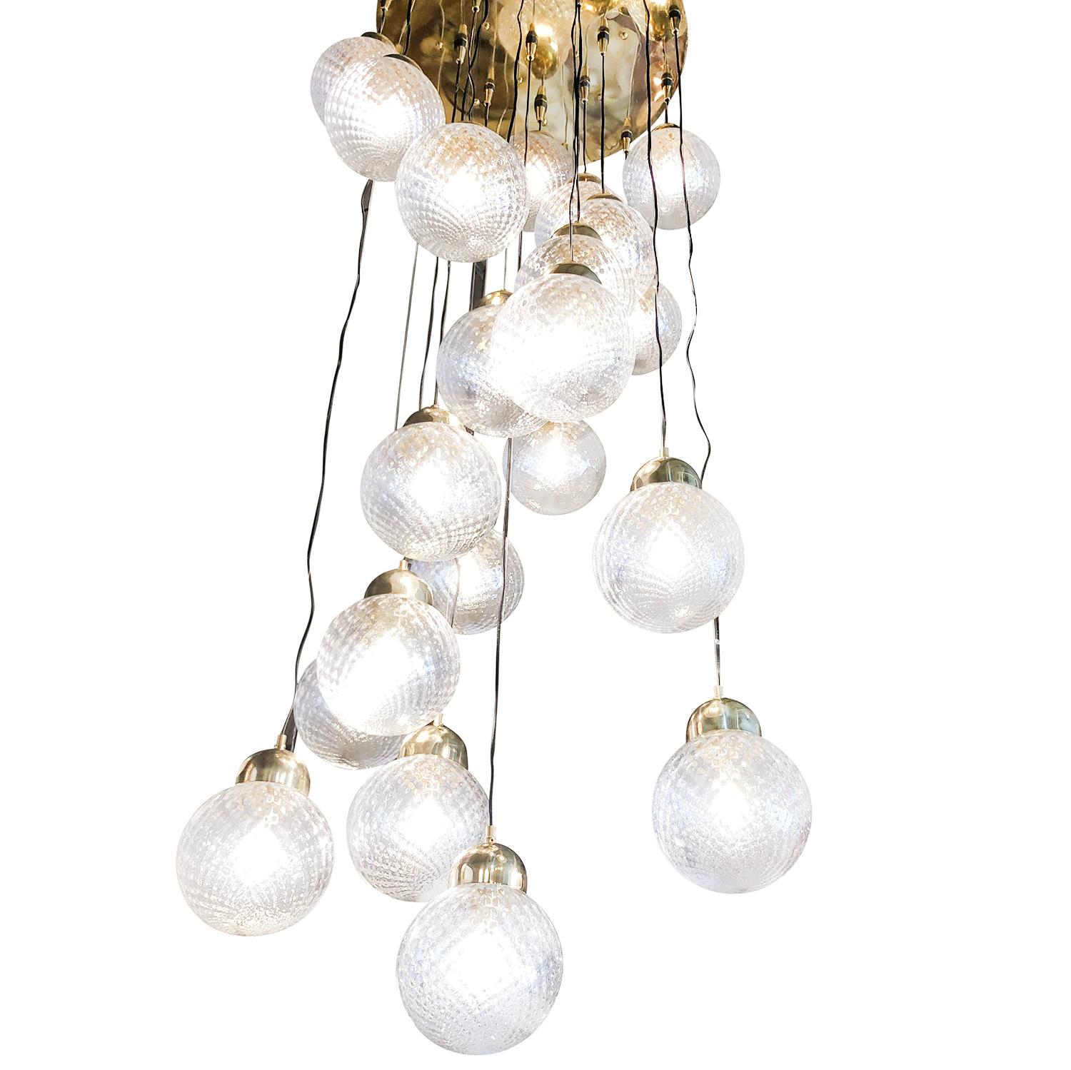 A very large Mid-Century Modern Italian ceiling light, lamp by an Italian designer. This chandelier is composed of a hand crafted brass frame plate and nineteen lightly frosted, hand blown Murano glass sphere bulbs and topped with brass pendant