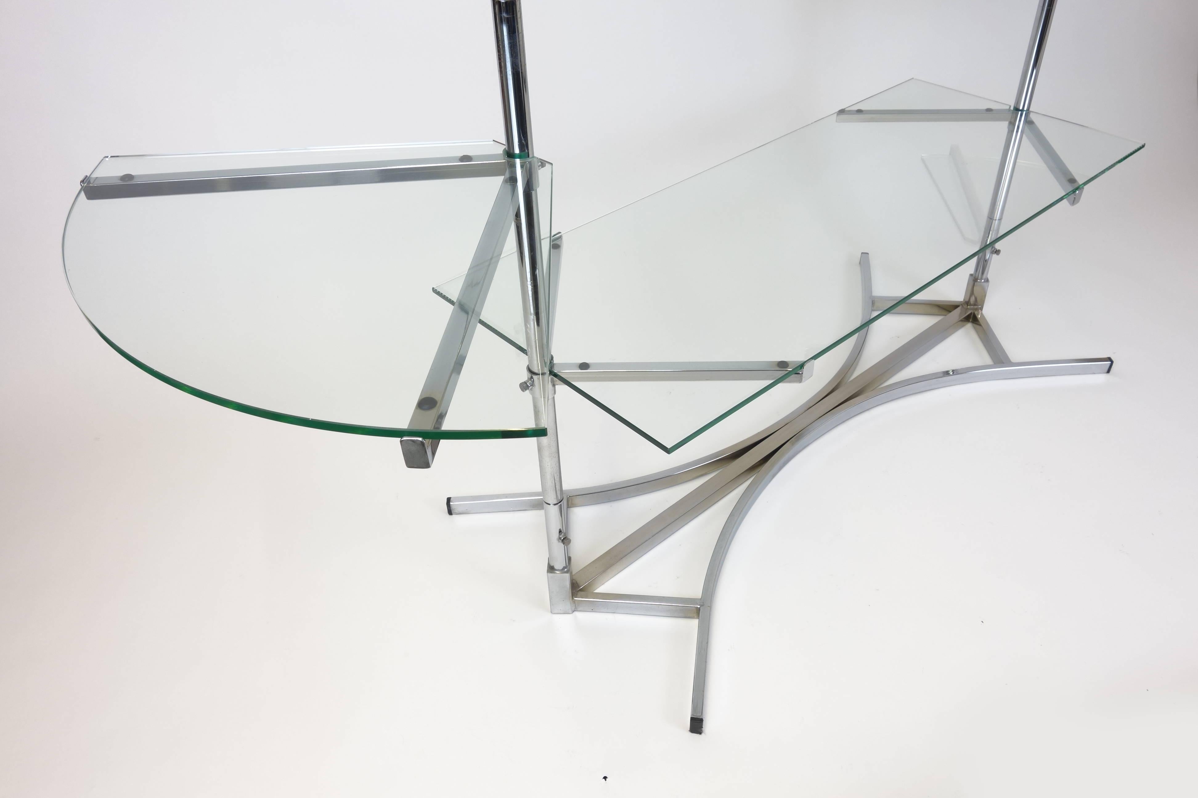 art-Deco-Glasregal aus Chrom des 20. Jahrhunderts im Stil von Jacques Adnet. Ein elegantes Glasregal, das von einem verchromten Metallrahmen getragen wird. Die mittleren Fächer und die Seitenteile können in der Höhe verstellt werden, außerdem kann