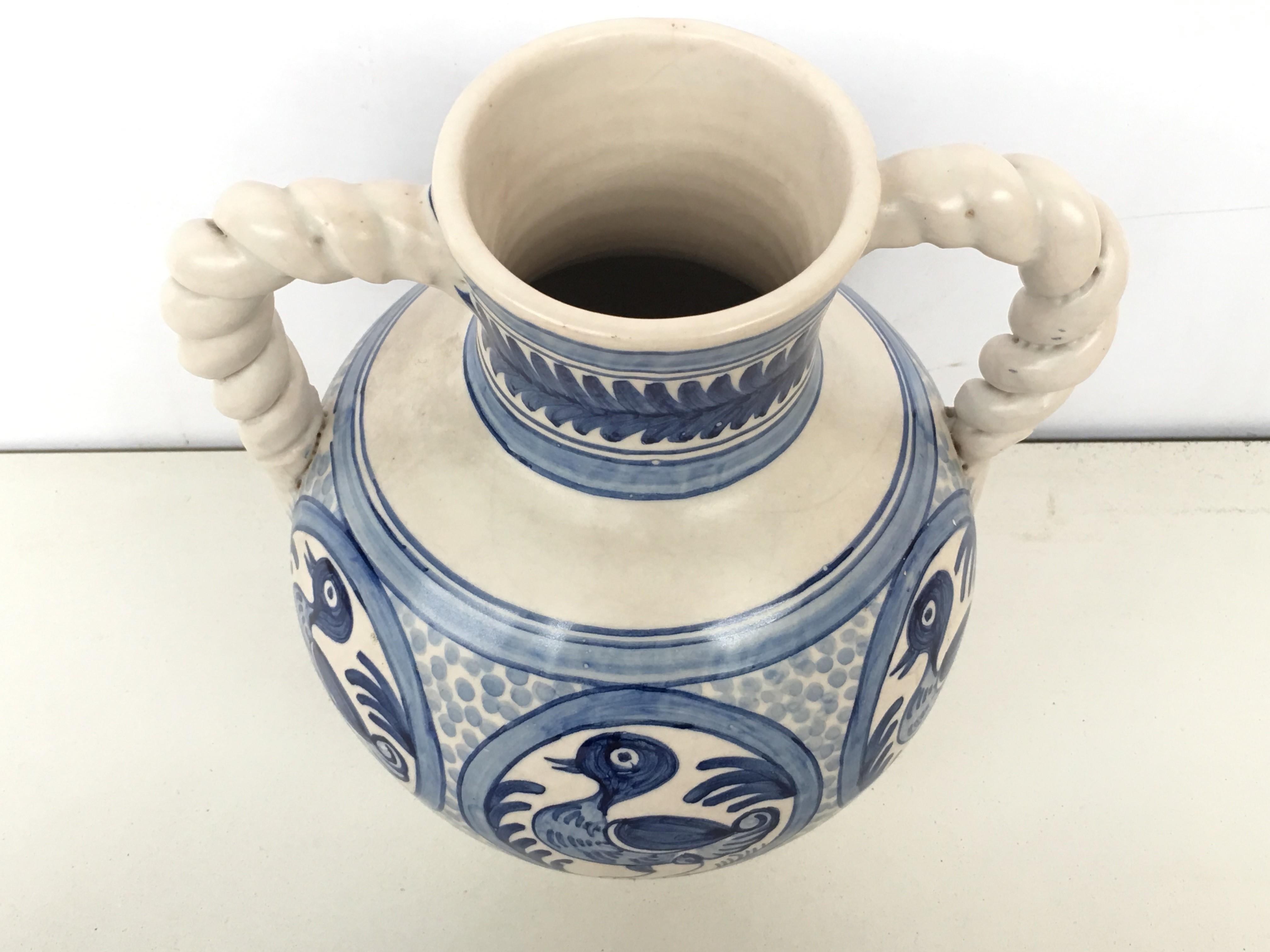 A striking Spanish glazed earthenware two-handled blue and white painted urn with foliate molded handles, the body underglaze blue ducks decorated very tipycal of this region.

Talavera de la Reina pottery is a craft made in Talavera de la Reina,