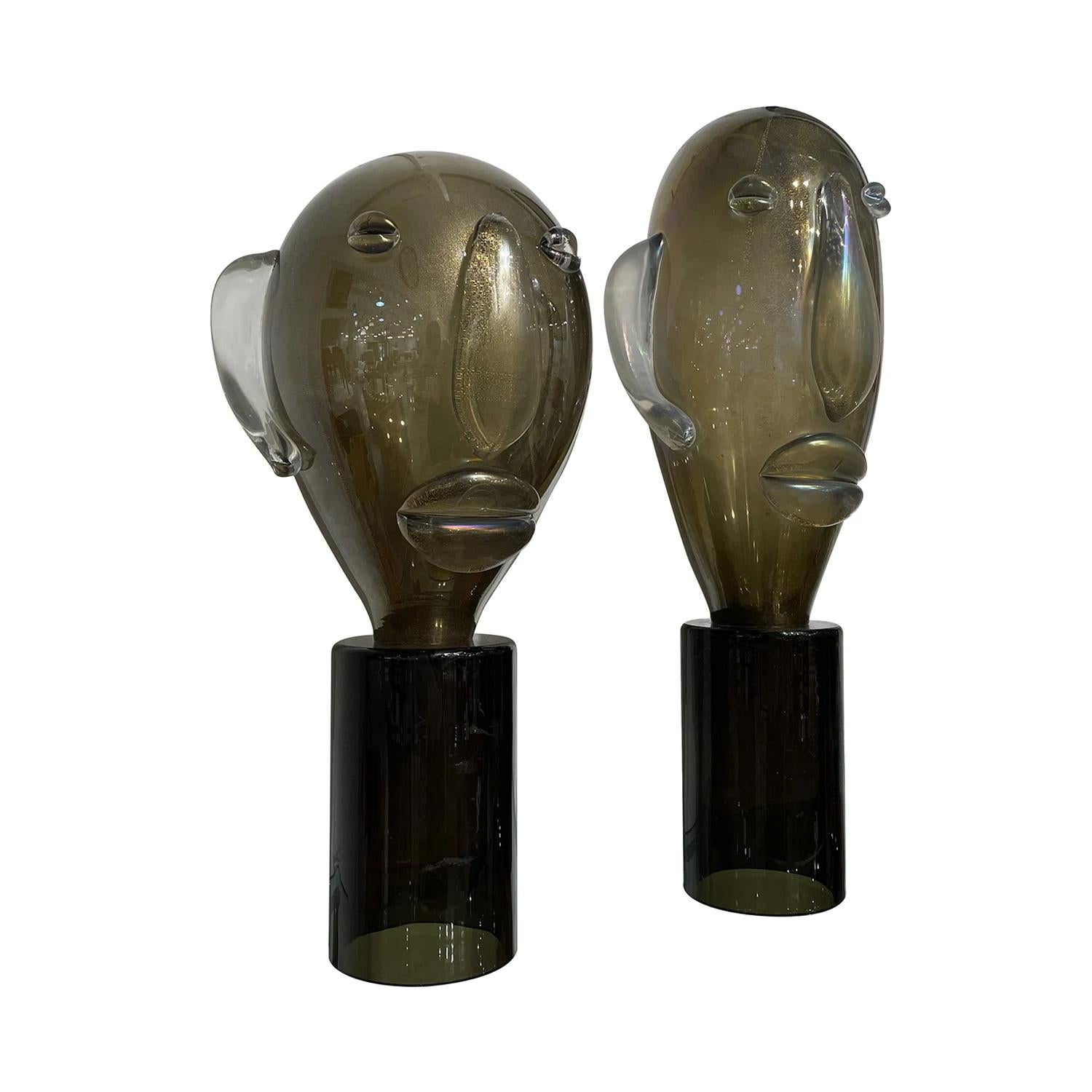 A late vintage Mid-Century Modern Italian similar pair of sculpture heads made of hand blown smoked Murano glass in the style of Picasso, in good condition. The detailed décor pieces are particularized with gold spots, resting on a round black base.