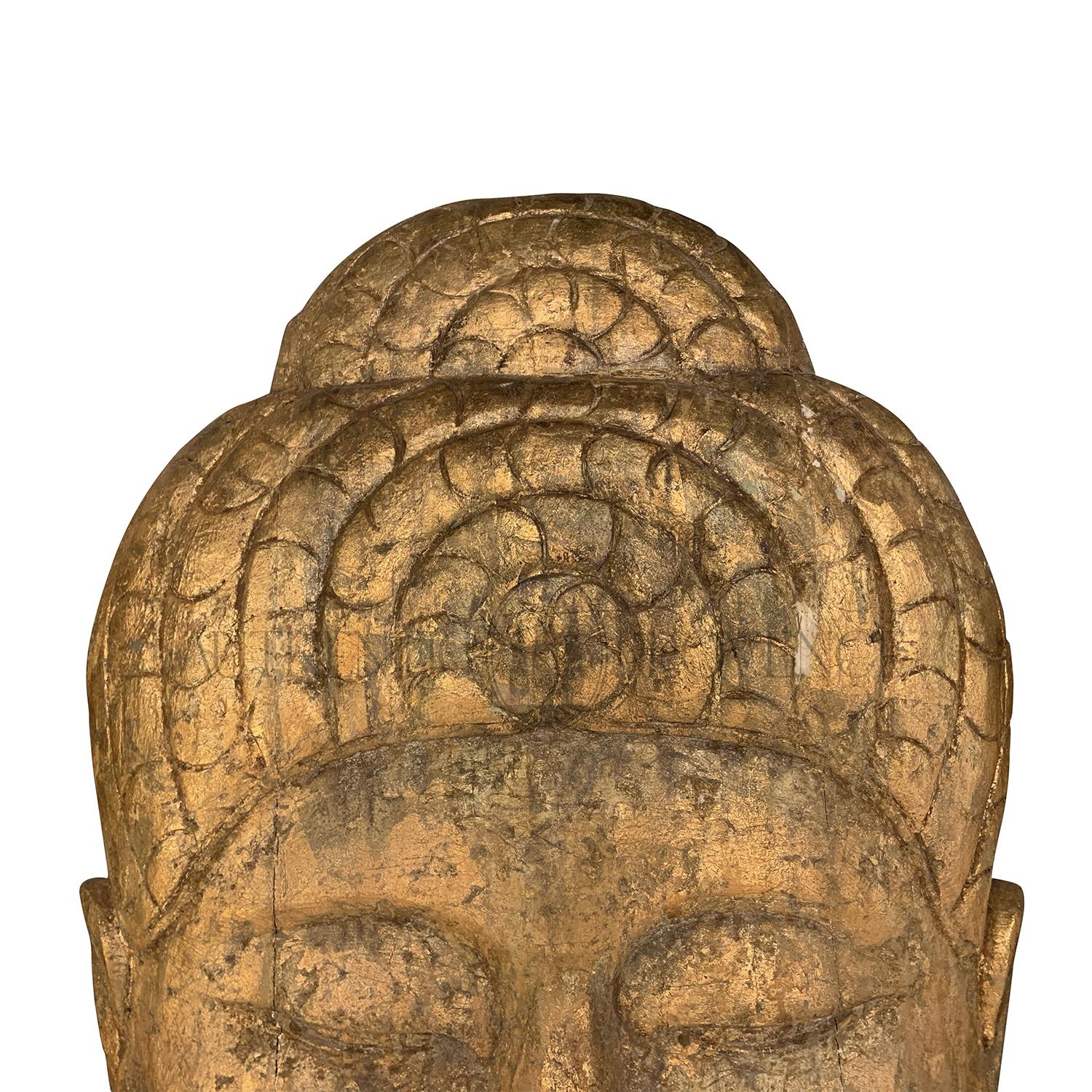 Ein goldbrauner, antiker asiatischer, übergroßer, dekorativer Buddha-Kopf für die Wandmontage in einem sehr großen Maßstab. Handgefertigt aus tropischem Holz und vergoldet, in gutem Zustand. Alters- und gebrauchsbedingte Abnutzung. CIRCA 1910,