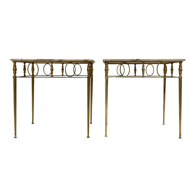A gold, vintage Art Deco French pair of side tables made of hand crafted polished brass with a cream-white marble top, in good condition. The small Parisian sofa tables are standing on four thin round legs, enhanced by detailed décor. Wear