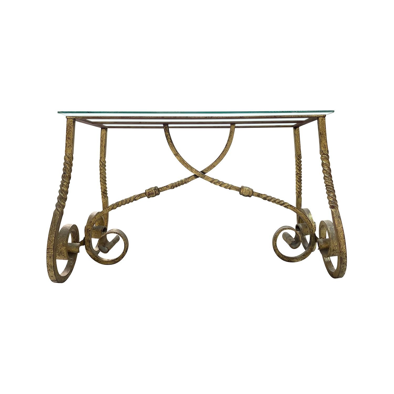 Ein goldener, französischer Art Deco Tisch aus handgefertigtem, vergoldetem Metall, in gutem Zustand. Der detailreiche rechteckige Beistelltisch besteht aus einer klaren Glasplatte, die auf vier gebogenen Beinen steht, die von zwei Armen gestützt