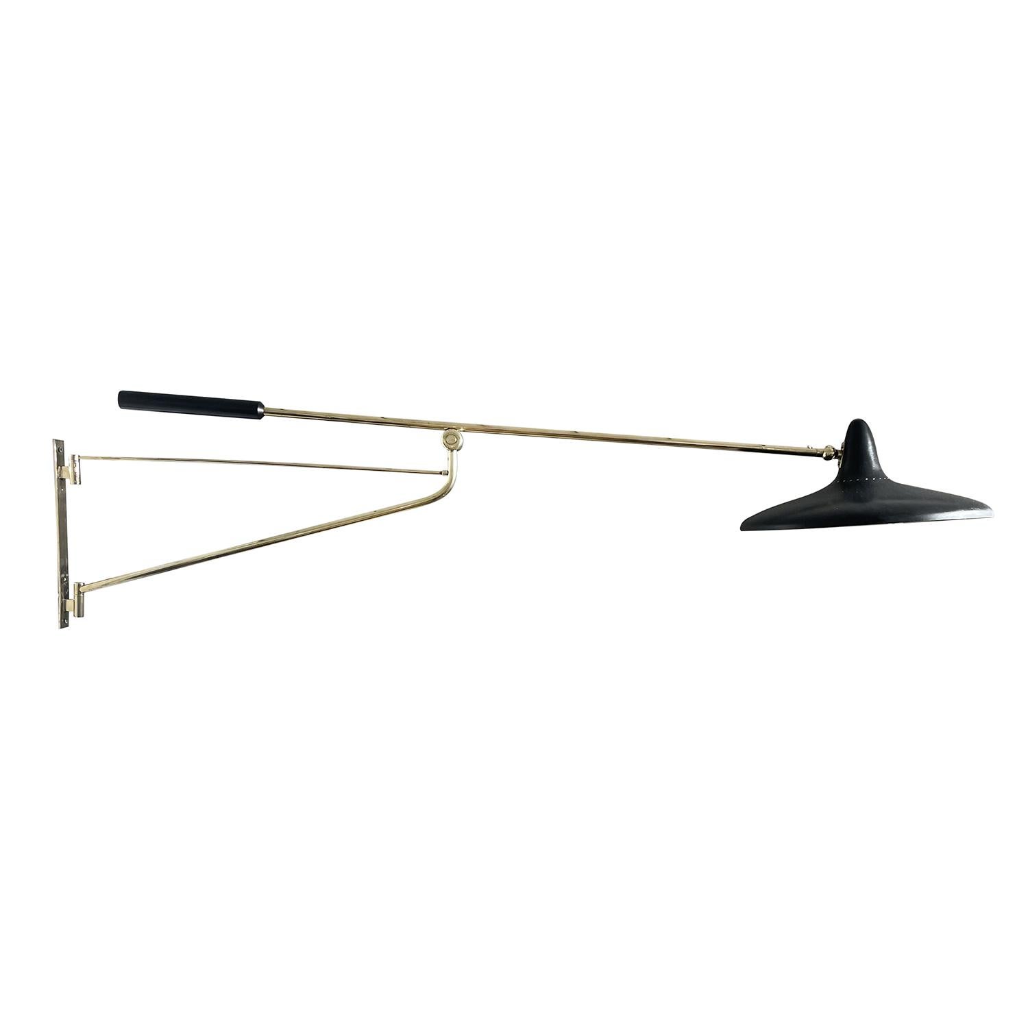 A gold-black, vintage Mid-Century Modern Italian reading wall lamp, light made of handcrafted polished brass, designed and produced by Stilnovo in good condition. The round lacquered aluminum shade is supported by a flexible stem, beam halted by two