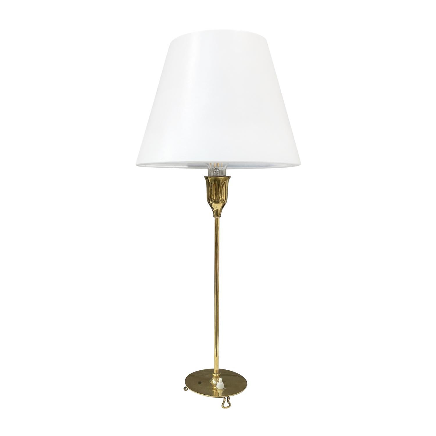 A gold, vintage Mid-Century Modern Swedish dressing table lamp with a new white round shade made of hand crafted polished brass, designed by Josef Frank and produced by Svenskt Tenn in good condition. The stem of the small Scandinavian desk light is