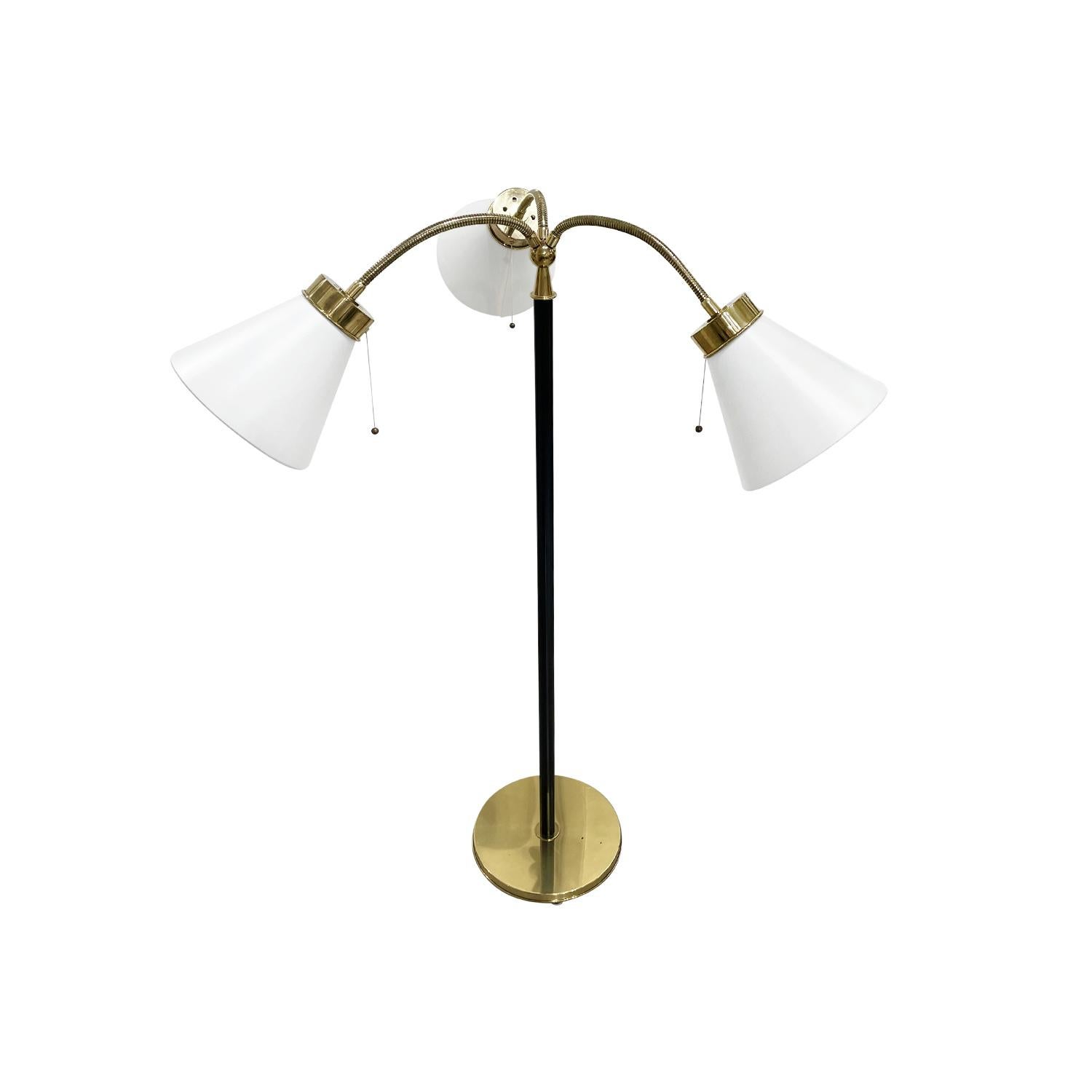 A gold-black, vintage Mid-Century modern Swedish floor lamp made of hand crafted iron and polished brass, designed by Josef Frank and produced by Svenskt Tenn in good condition. The Scandinavian light is composed with three new white conical shades,