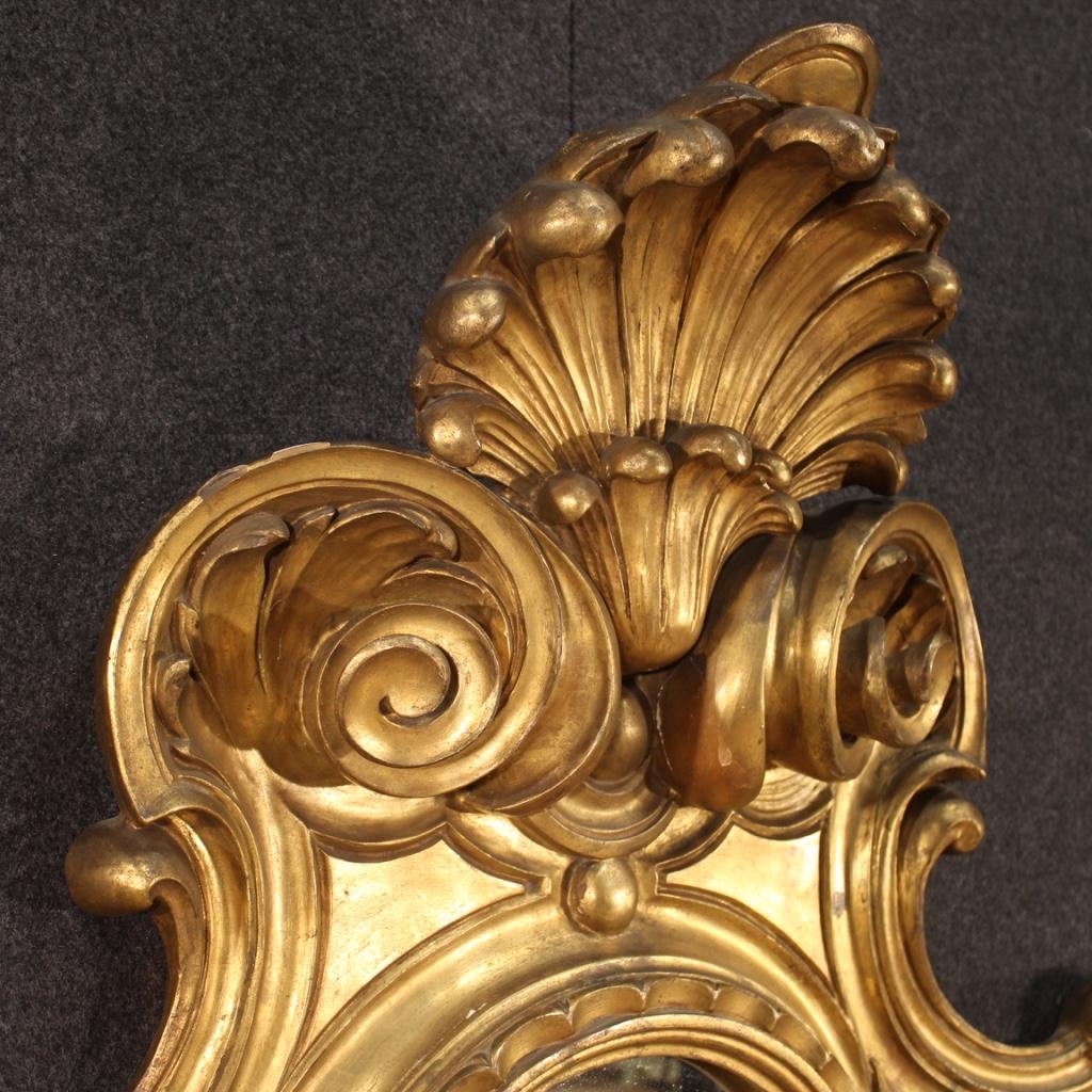 Large 20th century Italian wall light / mirror. Furniture in richly carved and gilded woods of exceptional quality, size and impact. Wall light to be fixed to the wall equipped with two candle holders placed under the mirror in gilded and chiseled