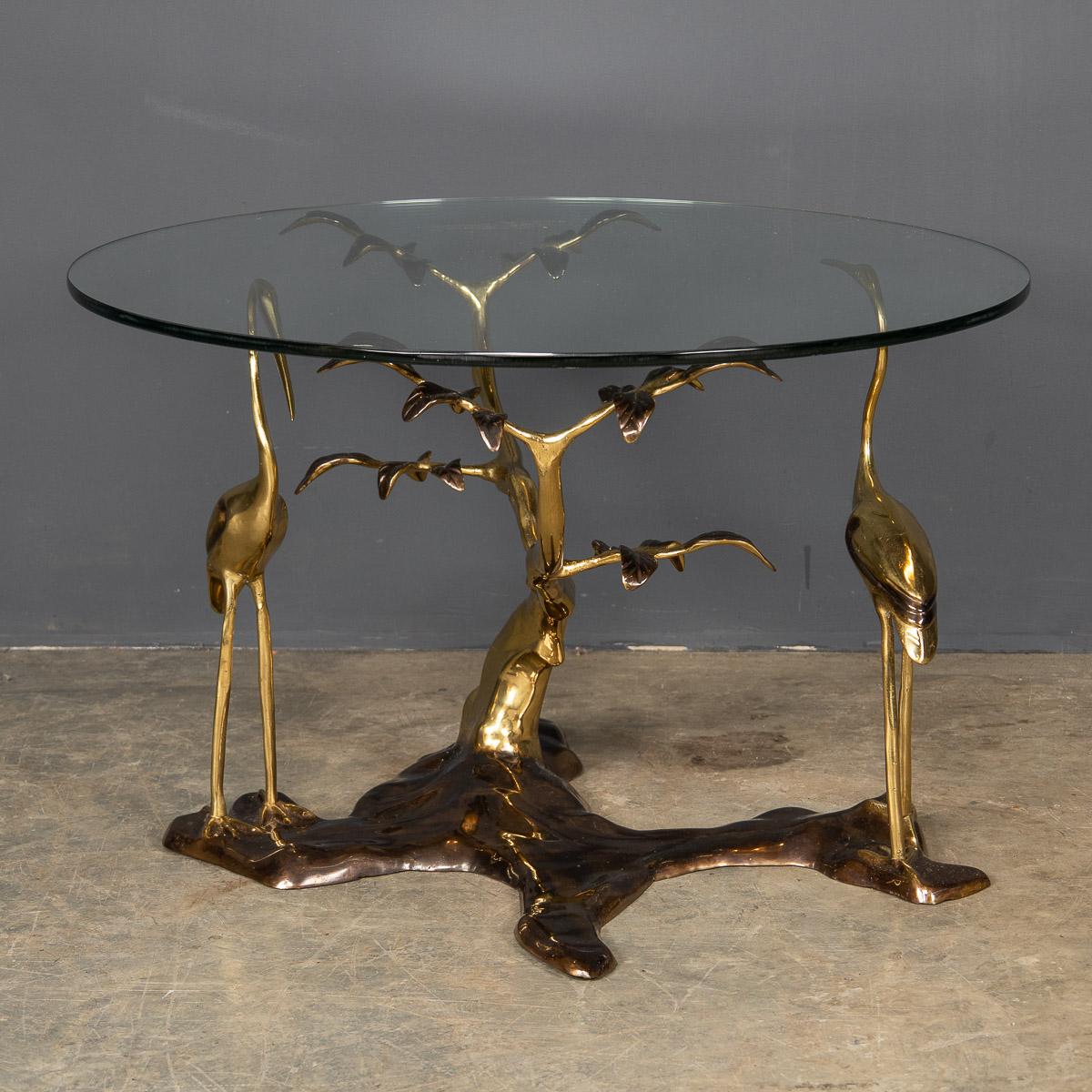 A stunning mid-20th century brass and bronzed coffee table depicting a pair of herons with a circular glass top.

Condition
In good condition - wear consistent with age.

Size (including glass)
Diameter: 70cm
Height: 44cm.