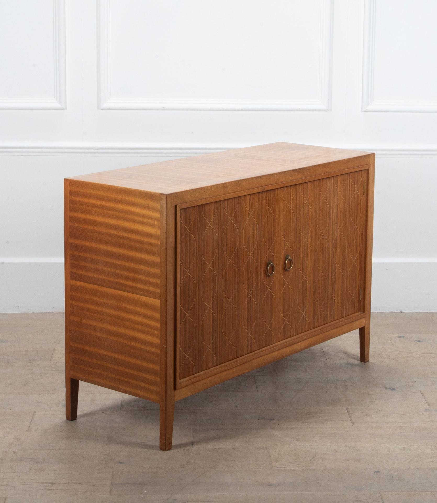 20th Century British, Gordon Russell 'Helix' mahogany sideboard.
Model No. R407, designed by David Booth.
Of rectangular form, enclosed by a pair of inset rosewood faced doors with incised interlacing vertical lines.
Brass ring handles, on tapering