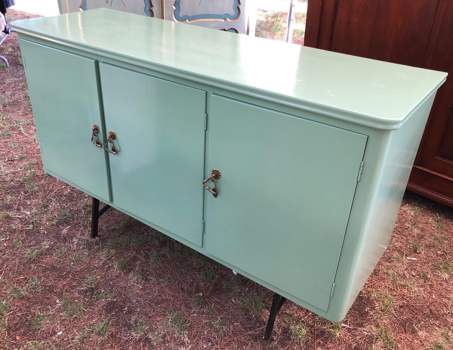 20th century green Italian sideboard, with three doors. 
The total height of the cupboard is 101 cm. while at the legs it is 33 cm.
It is a very useful piece of furniture in the kitchen and living room, it could very well contain your bar.
The