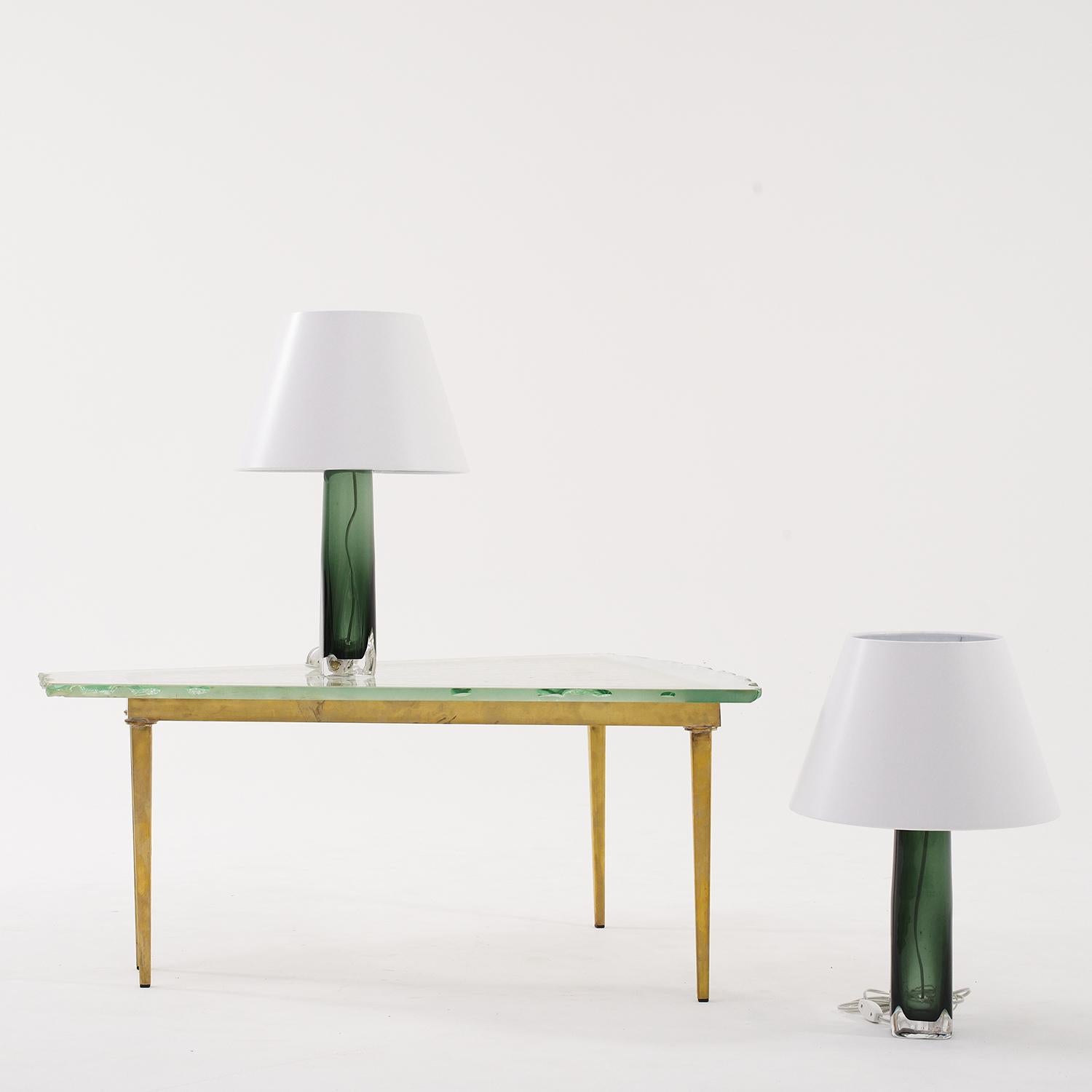 A dark-green, vintage Mid-Century modern Swedish pair of table lamps with a new white round shade, made of hand blown Orrefors glass, designed by Carl Fagerlund and produced, signed by Orrefors in good condition. The Scandinavian desk lights are