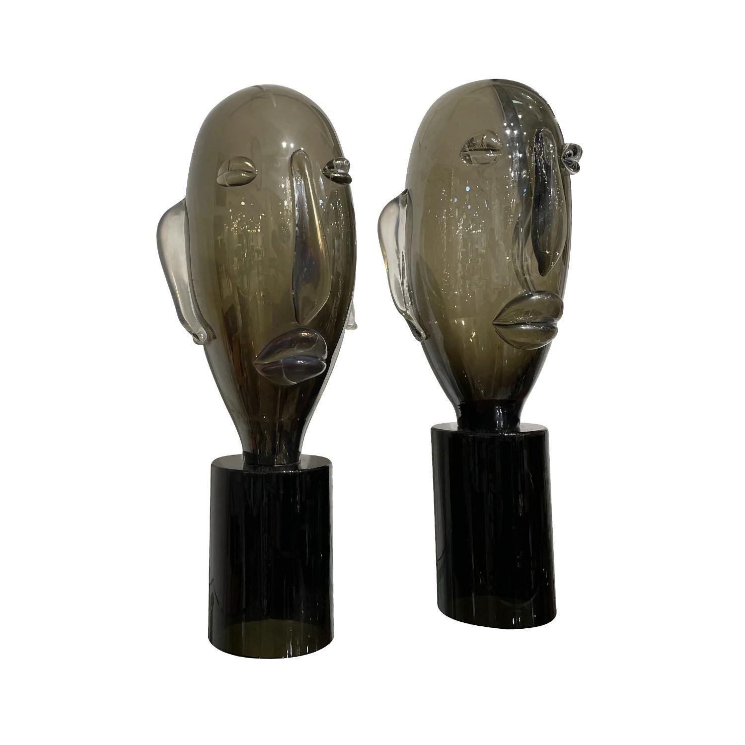 A late vintage Mid-Century Modern Italian similar pair of sculpture heads made of hand blown smoked Murano glass in the style of Picasso, in good condition. The detailed décor pieces are particularized with clear, white spots resting on a round