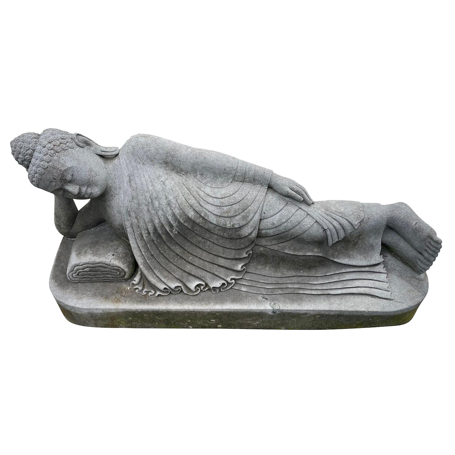 An early 20th Century vintage reclining Buddha garden statue in hand carved in lava stone elevated on simple rectangular base, in good condition. Weathered patina. Minor fading, due to age. Wear consistent with age and use. Circa 1920 - 1930,