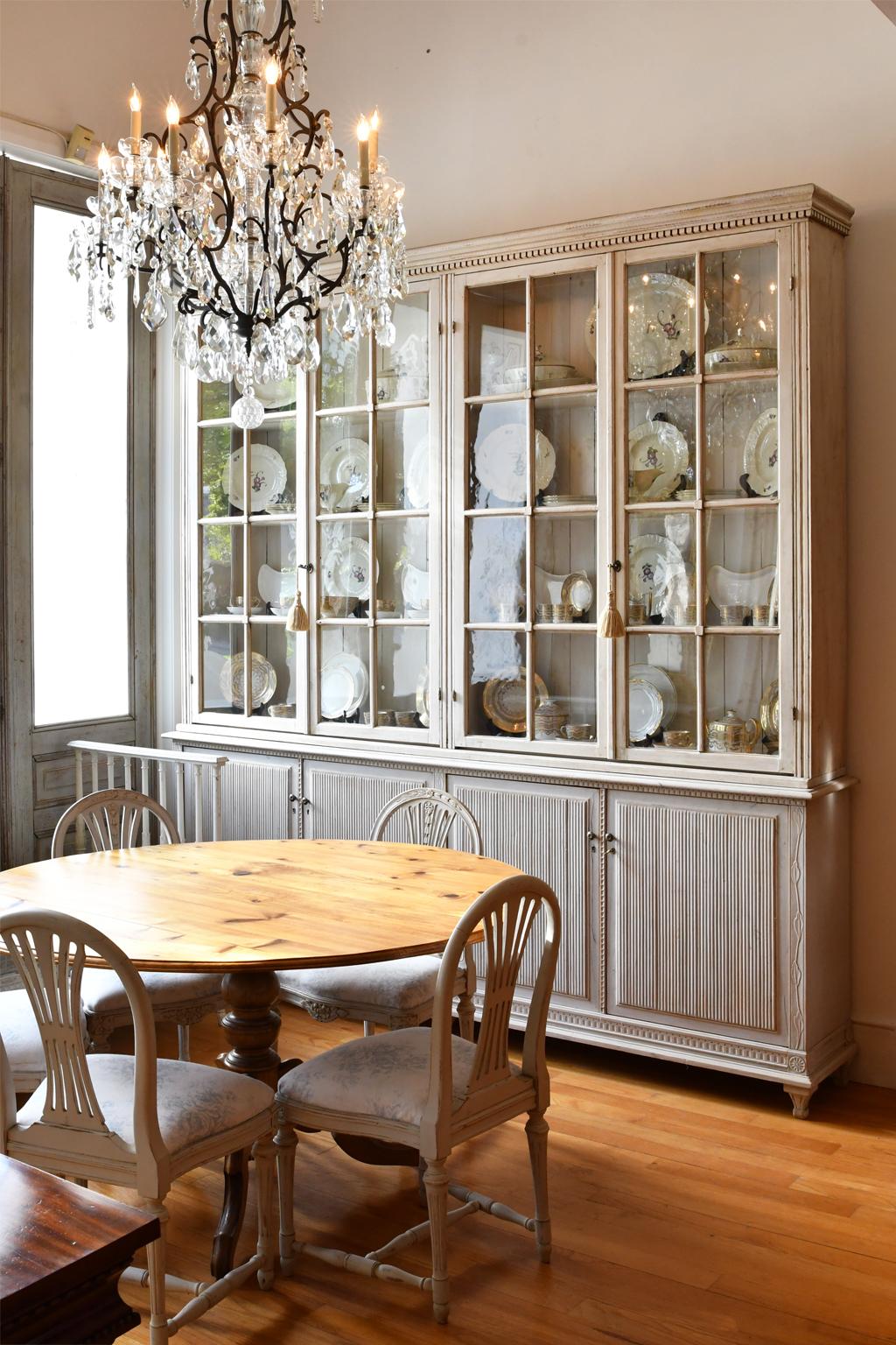 A large and very beautiful Swedish Gustavian-style bookcase with pale grey paint. Features four glazed upper doors with mullioned panels with original glass that open to three fixed shelves. Base has four tambour-front cabinet doors. Carved