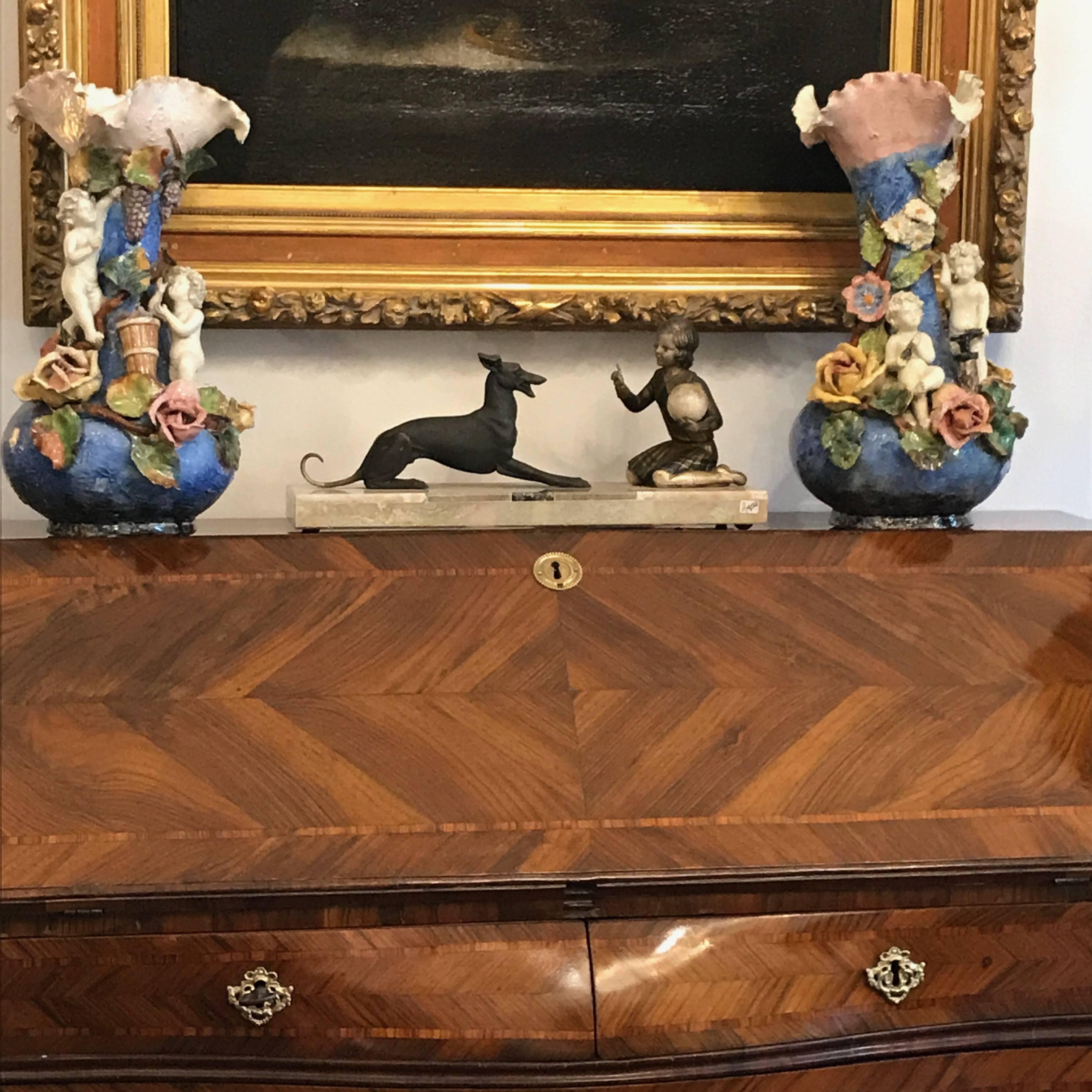 Art Deco French sculpture in silvered and patinated metal depicting a greyhound dog playing with a young girl. 

The girl is seated with a ball in her hand while giving orders to the lying dog, waiting to play. This sculpture conveys friend’s