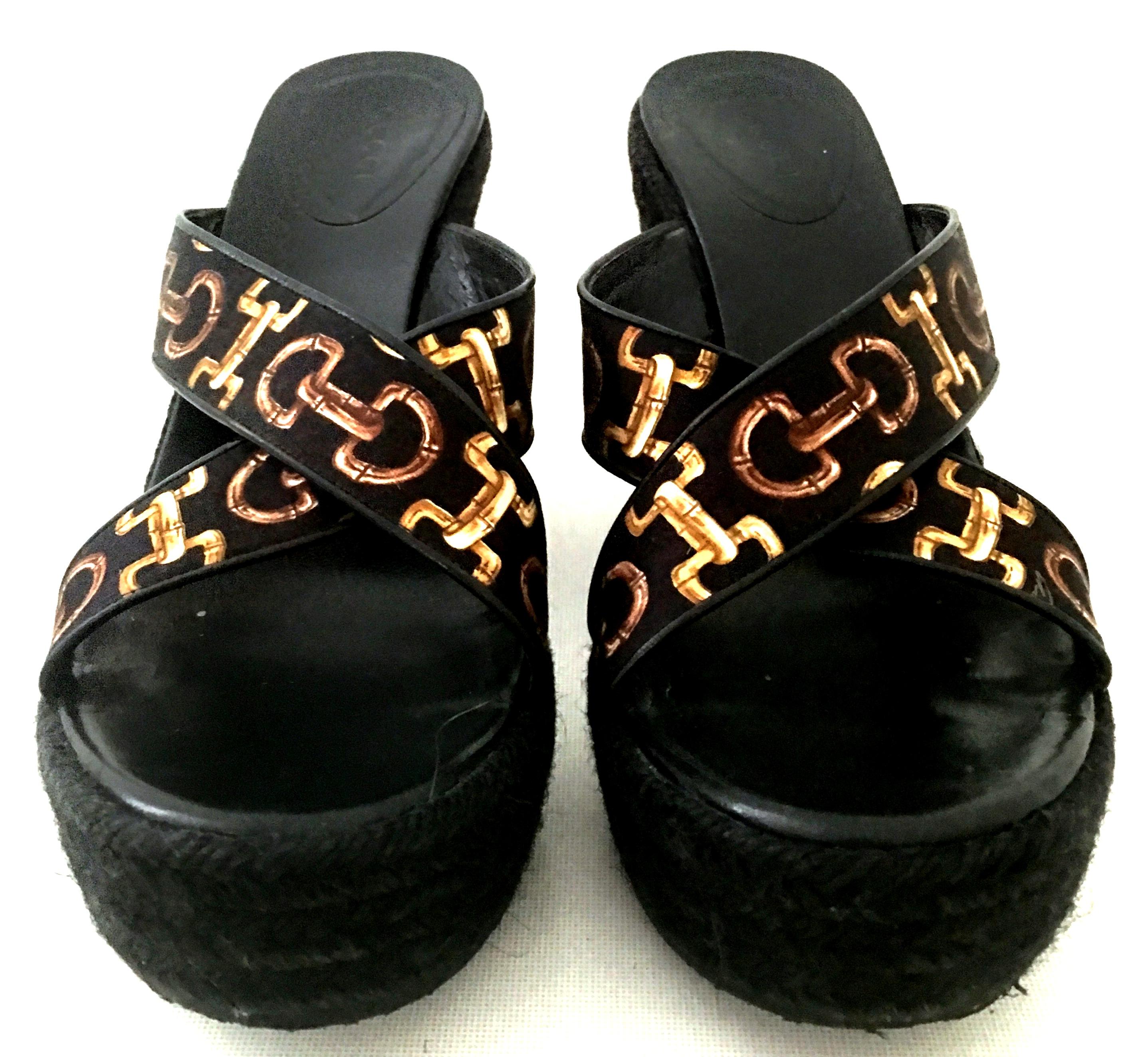 20th Century Pair of Gucci Silk Scarf Horsebit Raffia Wedge Platform Sandals, size 9.
These pristine Gucci silk scarf horsebit black and gold motif sandals feature the iconic 