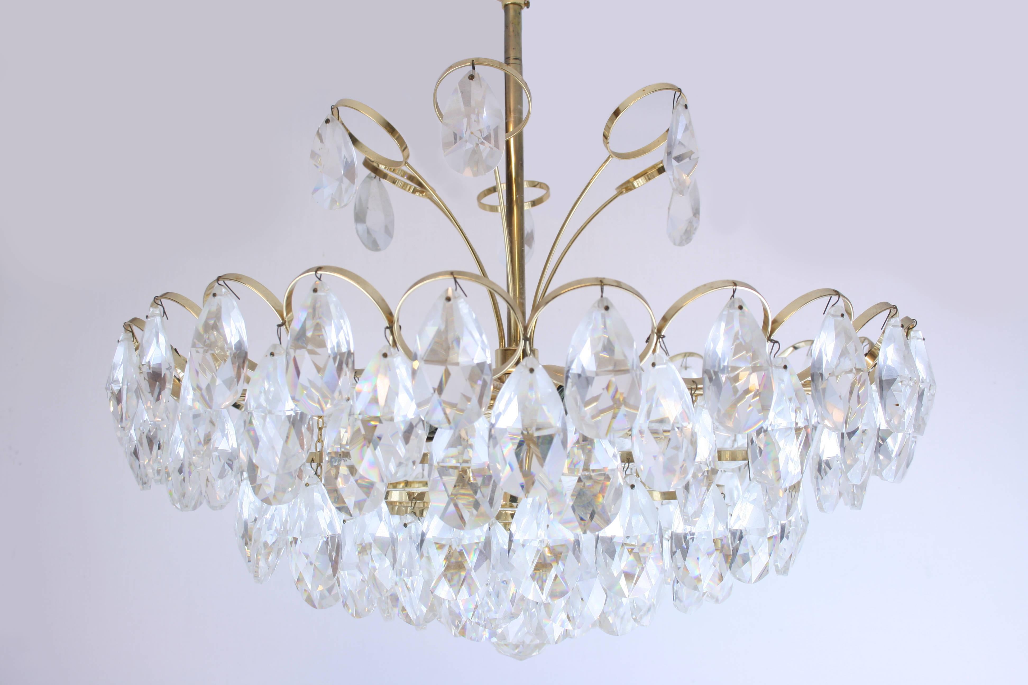 20th century gilded crystal brass chandelier by the German manufacturer Palwa. A masterpiece of artful German craftsmanship suitable as dining room pendant, bedroom pendant and distinguished living room pendant. An effectful luster with a strong
