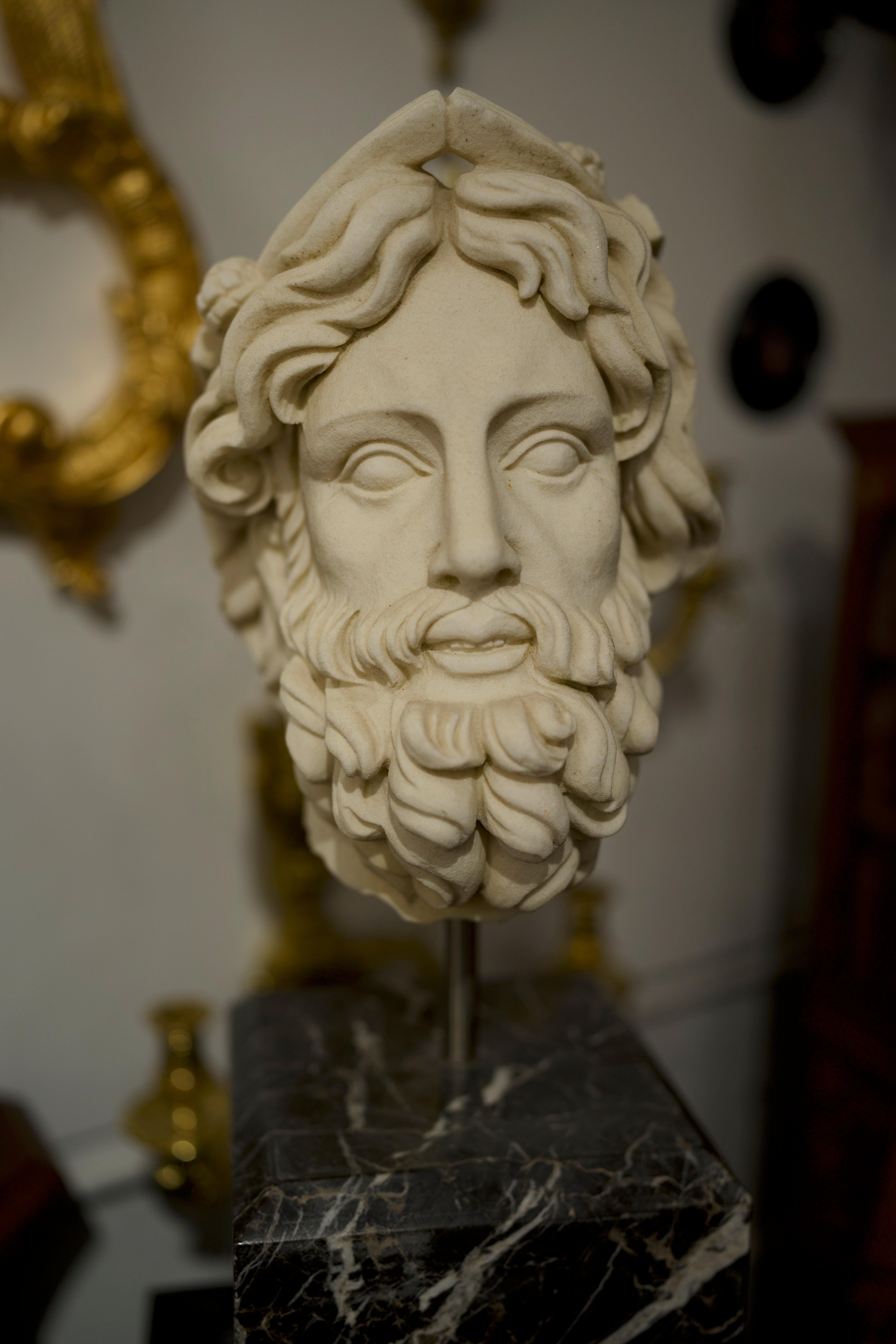 A beautiful 20th century hand carved marble Greek head bust with a black marble base. Stunning detail and skill from the artist, this piece would be fantastic for decor and home design.