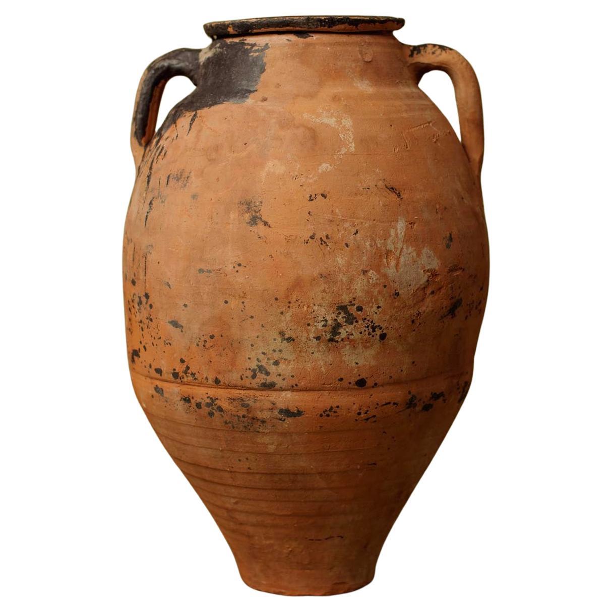 Questo orcio in terracotta del XX secolo proviene dall'Anatolia occidentale, dove le tradizionali tecniche di cottura a fiamma aperta producevano recipienti ricchi di texture e variazioni tonali. Utilizzato in origine per conservare l'olio d'oliva,