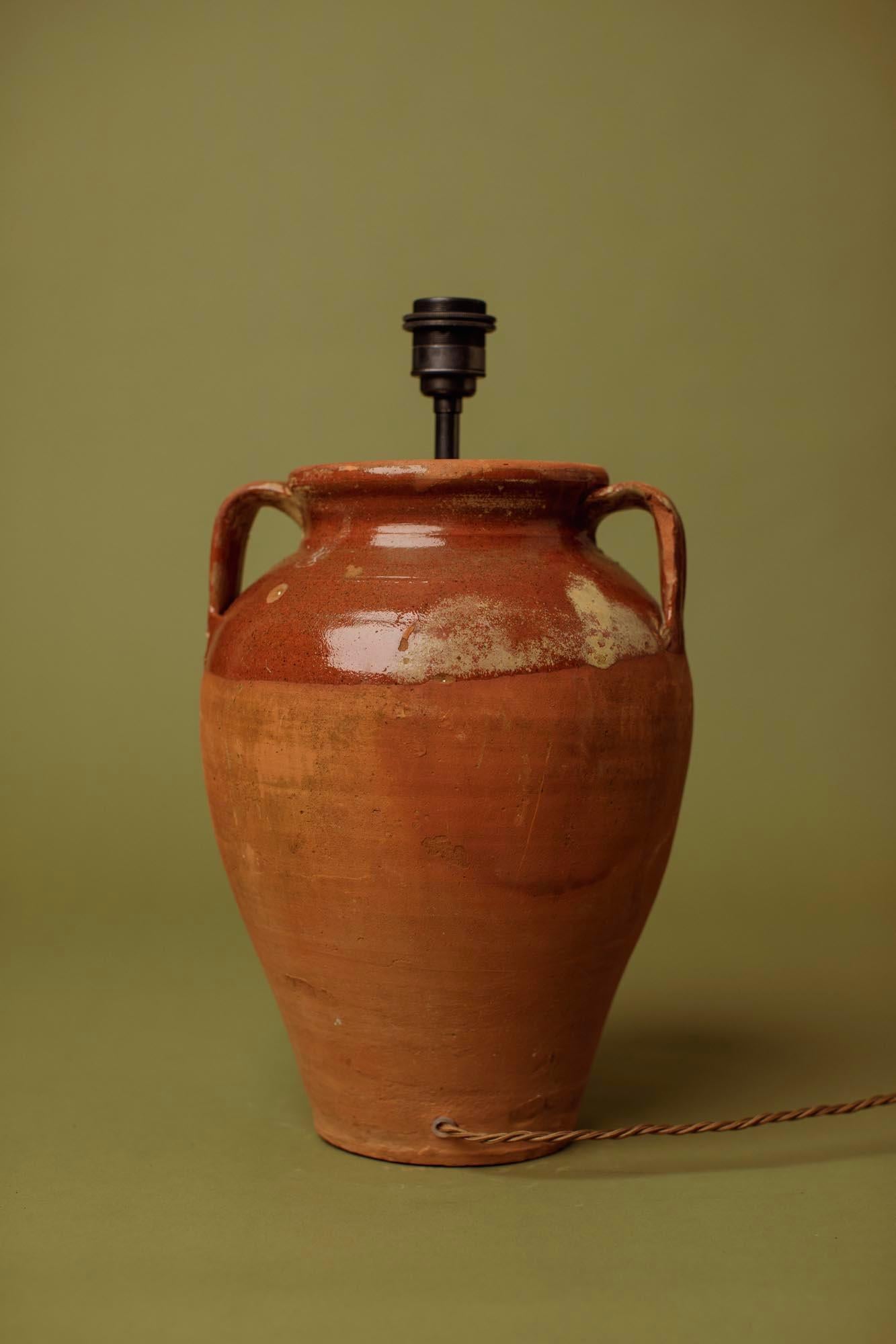 Cette lampe de table en terre cuite cuite à la main du 20e siècle capture la beauté élémentaire des traditions de la poterie anatolienne. Formé à la main à partir d'argile locale dense et cuit à feu ouvert, le récipient a développé sa surface