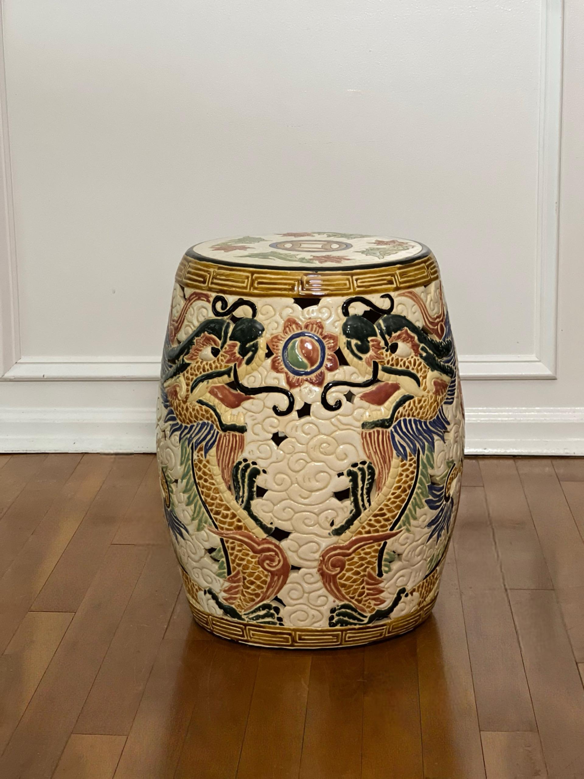 Mid 20th century Chinese dragon ceramic garden stool or side table.  Invigorate a room with this boldly decorated stool featuring dramatic dragons amongst carved swirls of white clouds and pierced sides in a vibrant color palette of hand painted