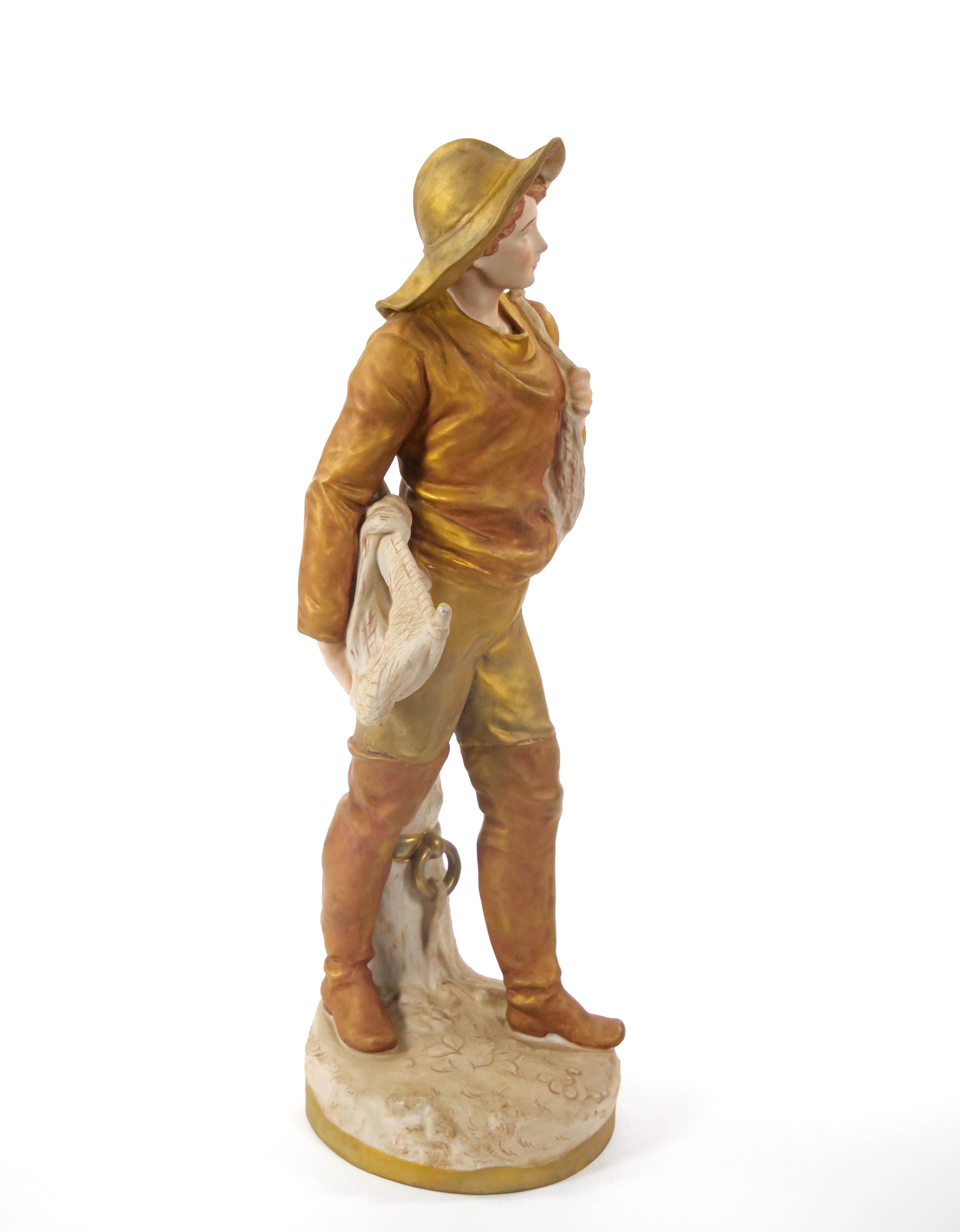 Esta exquisita escultura de porcelana de principios del siglo XX de Royal Dux, fabricada en la República Checa, es una asombrosa representación de arte meticuloso y elegancia atemporal. La escultura muestra a un hombre vestido de época, con sombrero