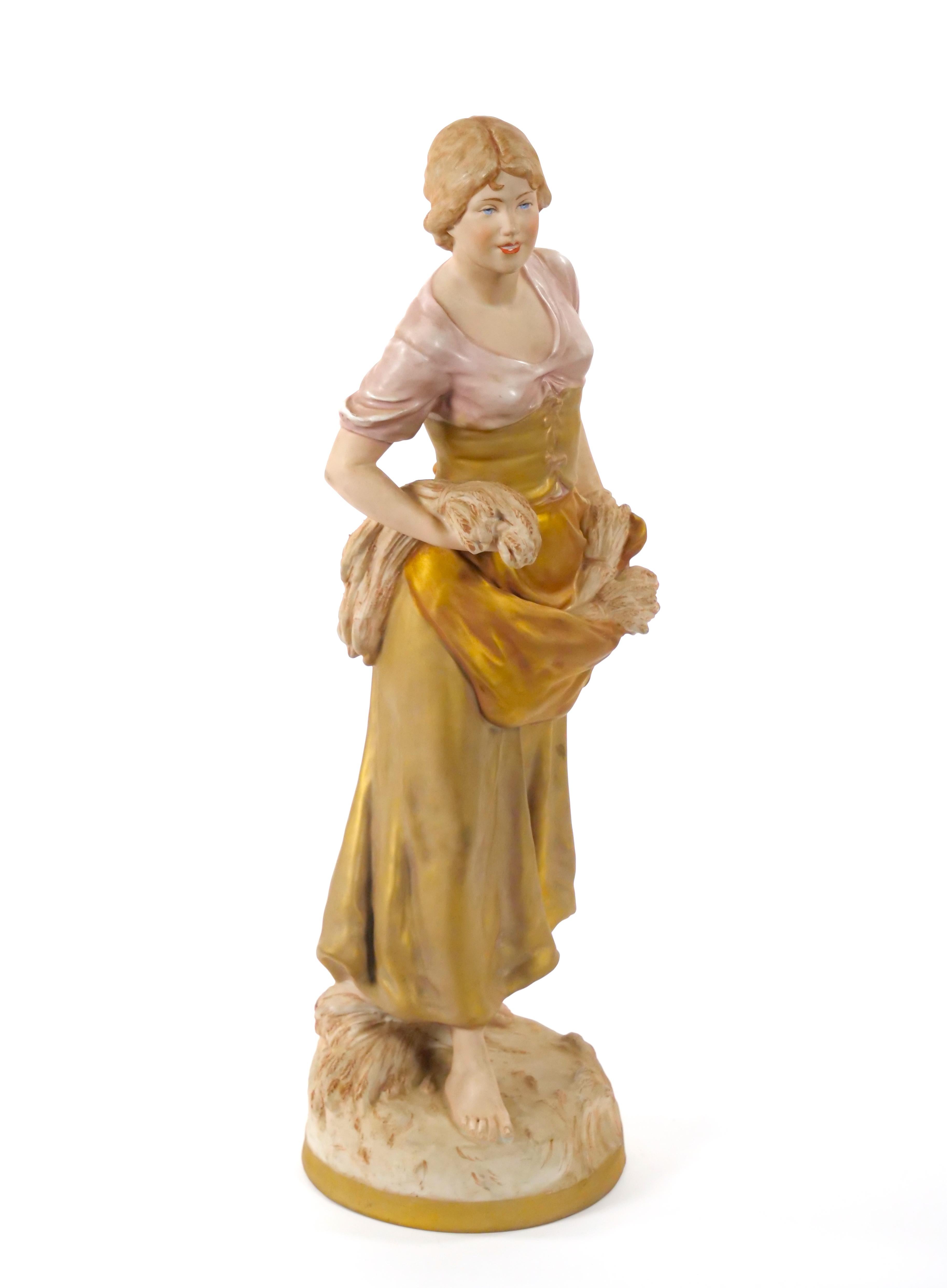 Esta exquisita escultura de porcelana de principios del siglo XX de Royal Dux muestra la fina artesanía y los detalles artísticos característicos del renombrado fabricante checo. La escultura representa a una mujer vestida con un elegante atuendo de