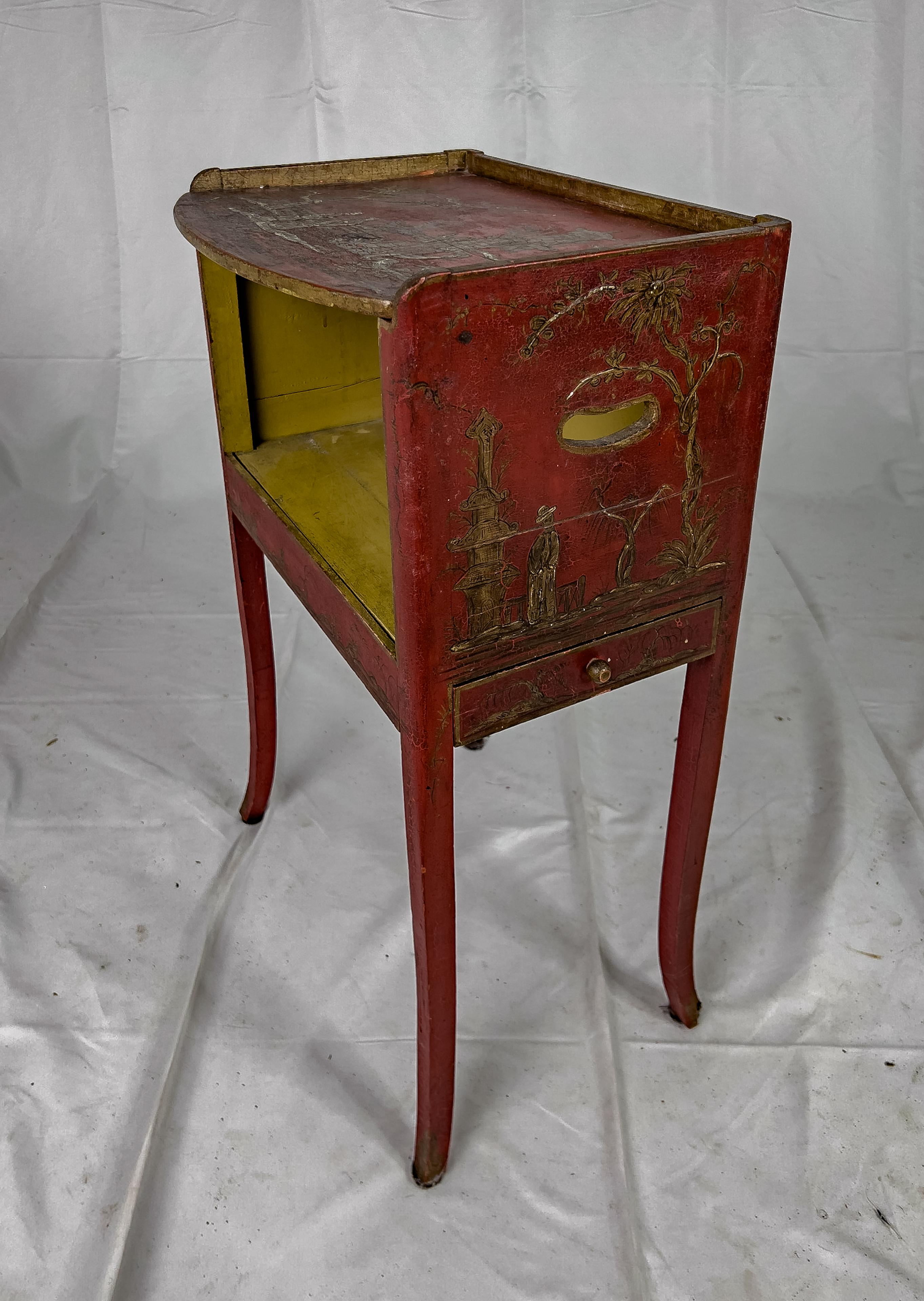 20th Century Hand Painted Red Chinoiserie Side Table. This piece is hand painted on all sides, has cut out handles on the sides, a discreet drawer on one side, top surface has an open recess underneath for display and splayed legs.