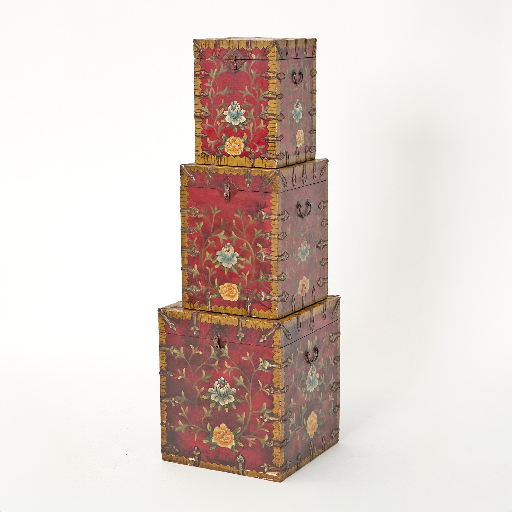 Un ensemble exceptionnel de trois malles en bois laqué rouge peintes à la main au XXe siècle, chacune présentant un mélange harmonieux d'art et de fonctionnalité. Les extérieurs sont recouverts d'une laque rouge riche et profonde, rehaussée par des