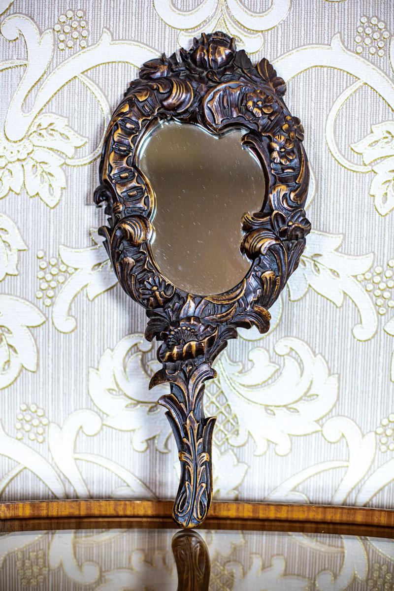 We present you a small handheld mirror in a carved walnut frame.

The item was manufactured before 1939.

The mirror is in very good condition.
