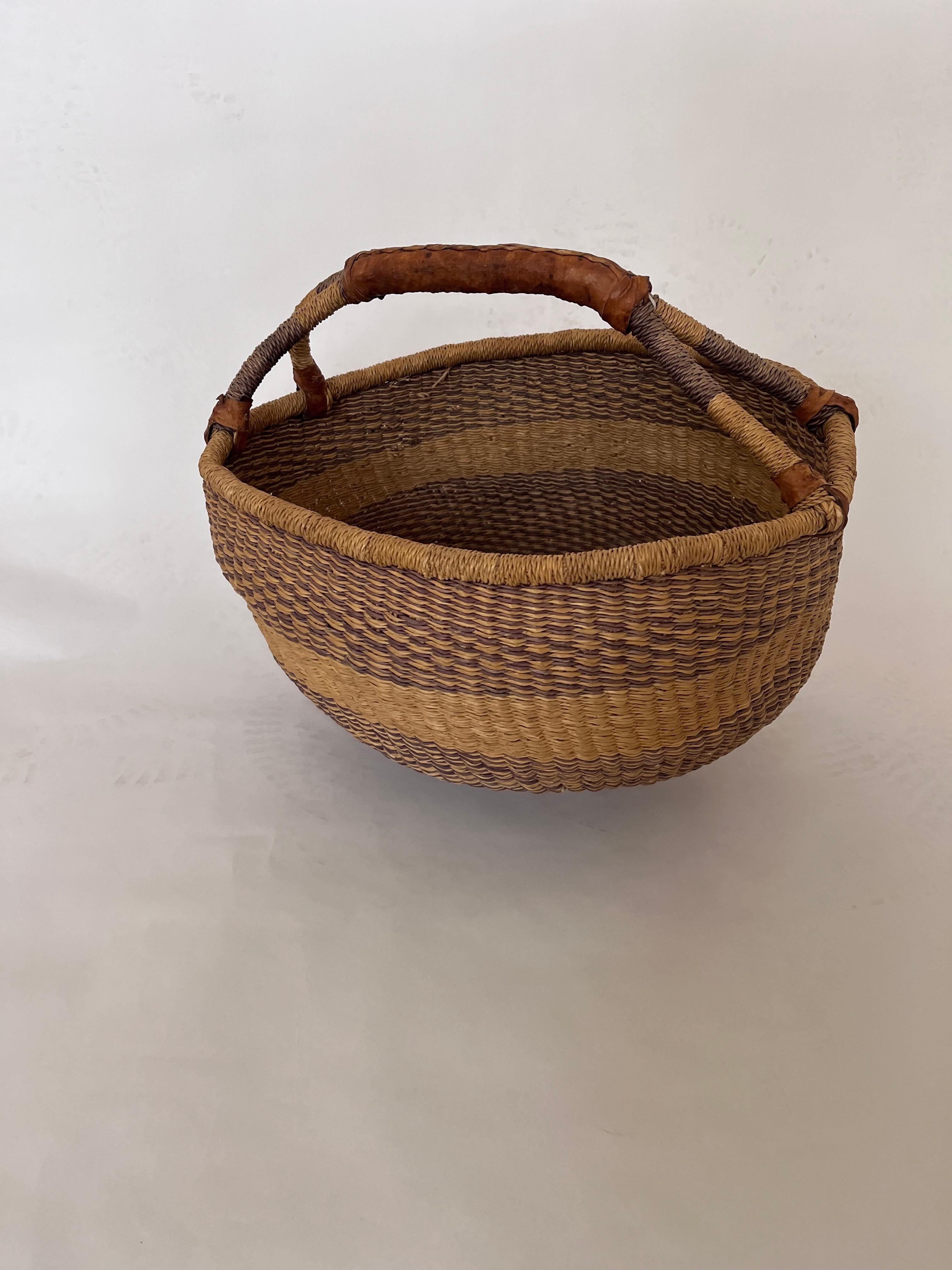 Cesto Bolga africano intrecciato a mano del XX secolo con manico in pelle

Questo splendido cesto Bolga del XX secolo, intrecciato a mano, è un pezzo organico dalle forme morbide realizzato nella regione di Bolgatanga, nel Ghana settentrionale, un