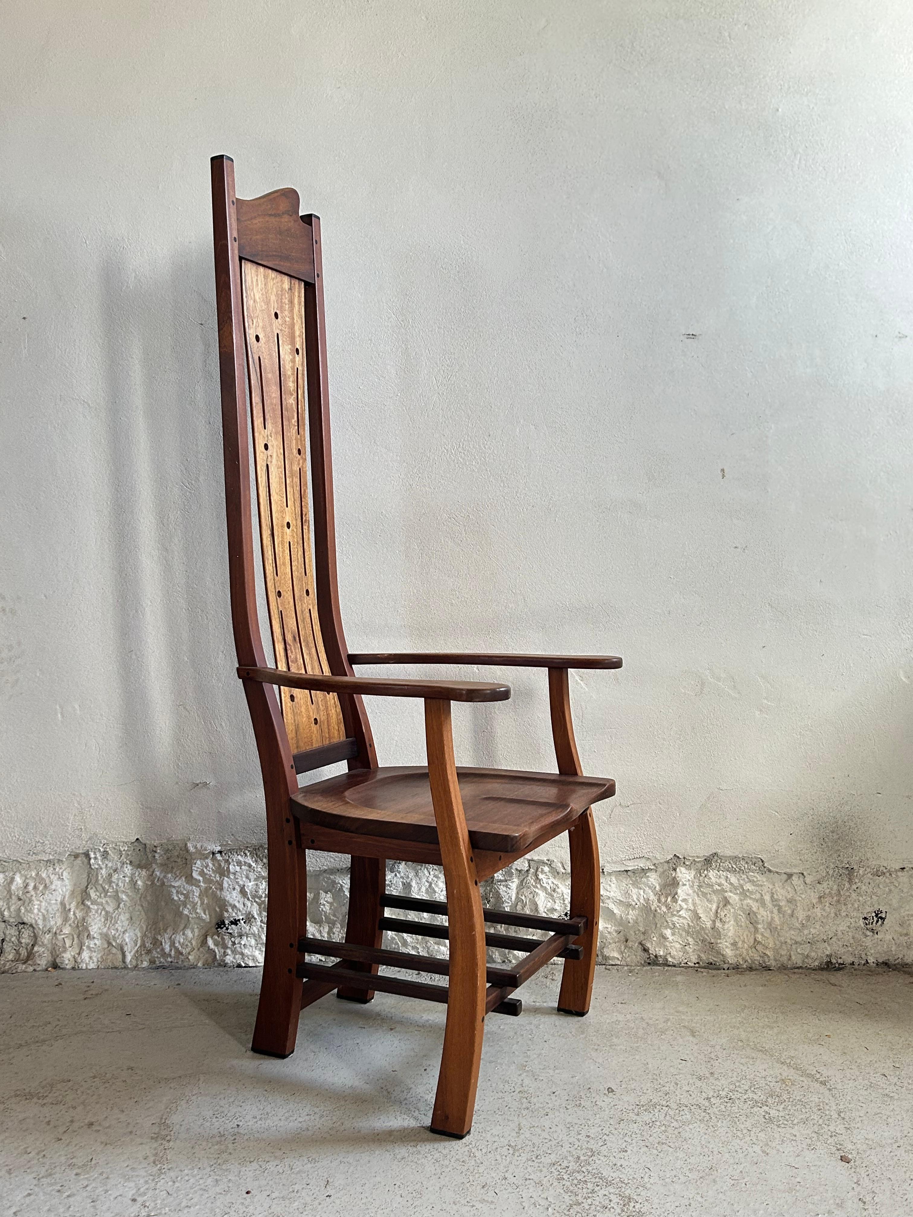A beautifully handcrafted high-back armchair, embodying the essence of the Arts and Crafts movement. Made from solid wood, this chair features meticulous joinery and a rich, natural patina that highlights its artisanal craftsmanship.

The tall,