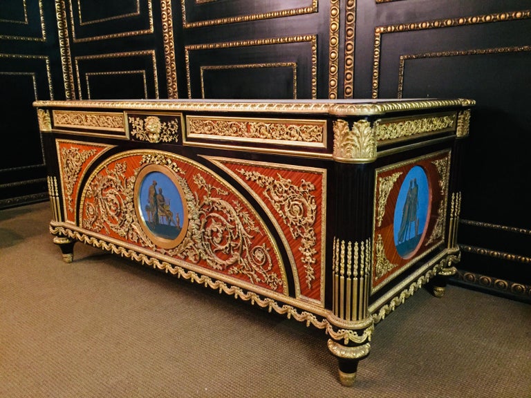 Exotic veneer on solid oak and wood. Extremely finely chased and rich bronze applications. Rectangular body. A hand painted picture badge on the front and side view. Gilded bronze decorations embedded on the front, flanked by conical, fluted legs