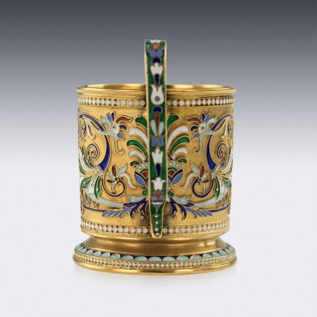 Antique 20th century Imperial Russian solid silver-gilt and cloisonné enamel tea glass holder, circular with upright scroll handle, spreading foot, body profusely decorated with floral motifs in vary-colored cloisonné enamel within borders of white