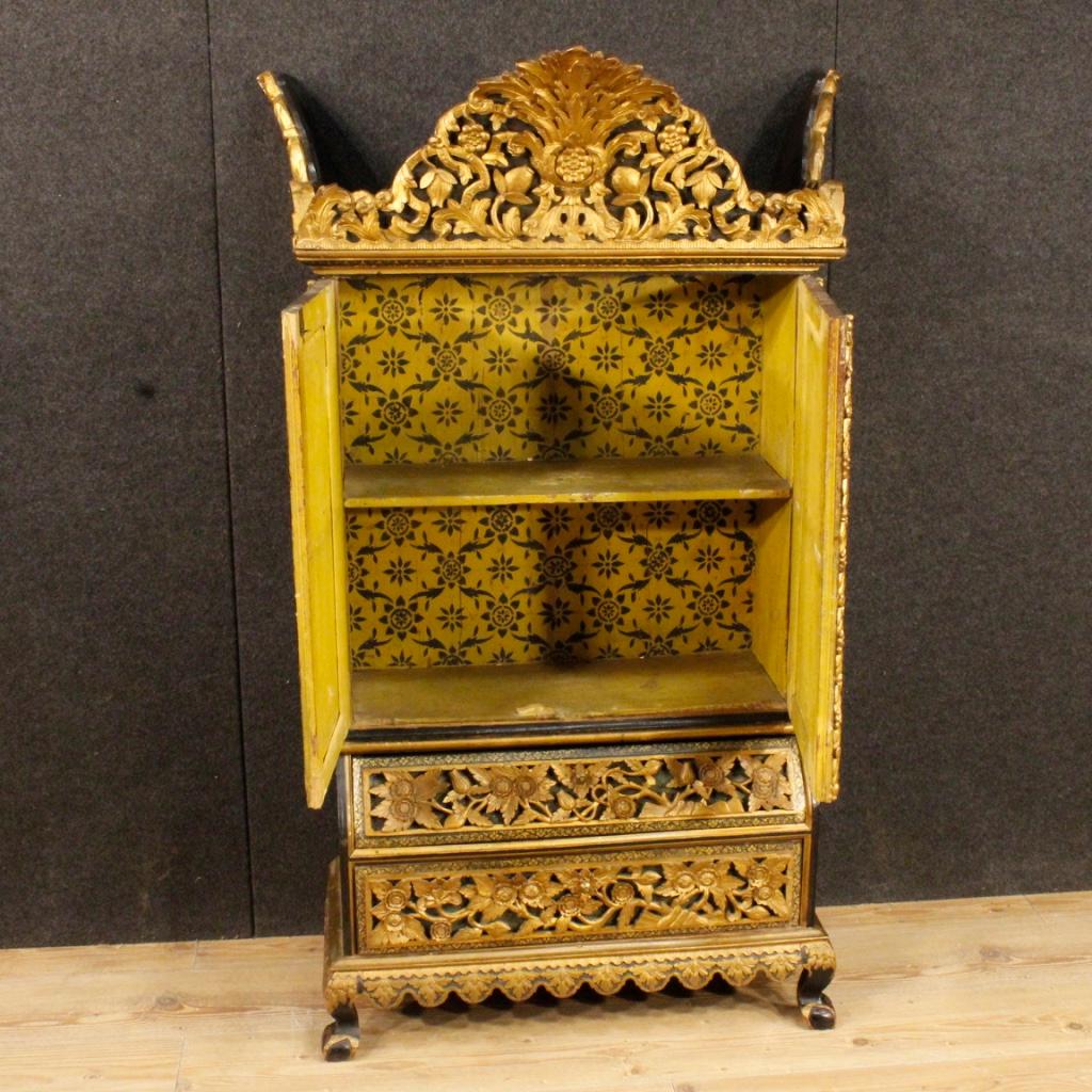 20th century Indian cabinet. Furniture in richly carved, painted and gilded wood of pleasant decor. Cabinet of small measure, it can be easily placed in different points of the house. Cabinet with two doors and two drawers at the base, of fair