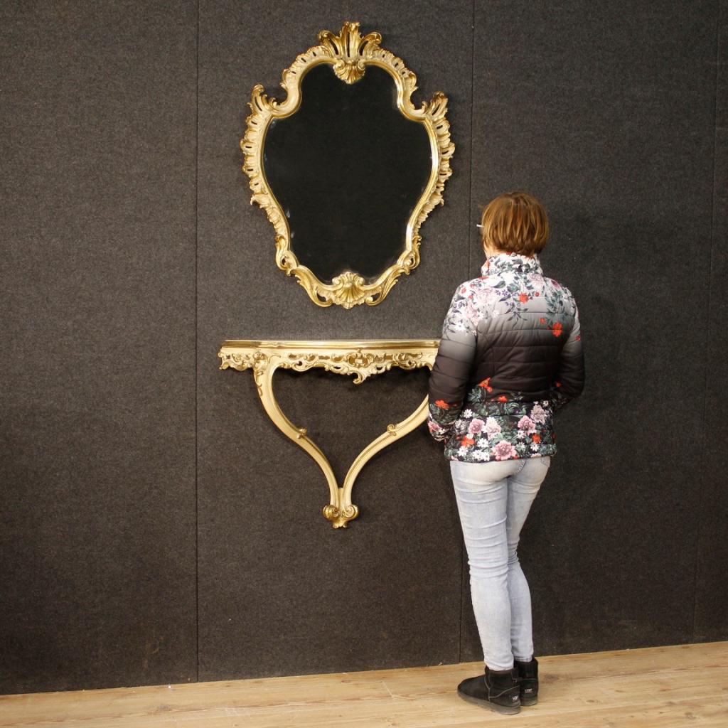 Console italienne avec miroir du 20ème siècle. Meubles en bois joliment sculptés, laqués et dorés d'une belle ligne dans le style vénitien. Console à accrocher au mur équipée d'un plateau en bois de caractère peint avec des décors floraux. Miroir de